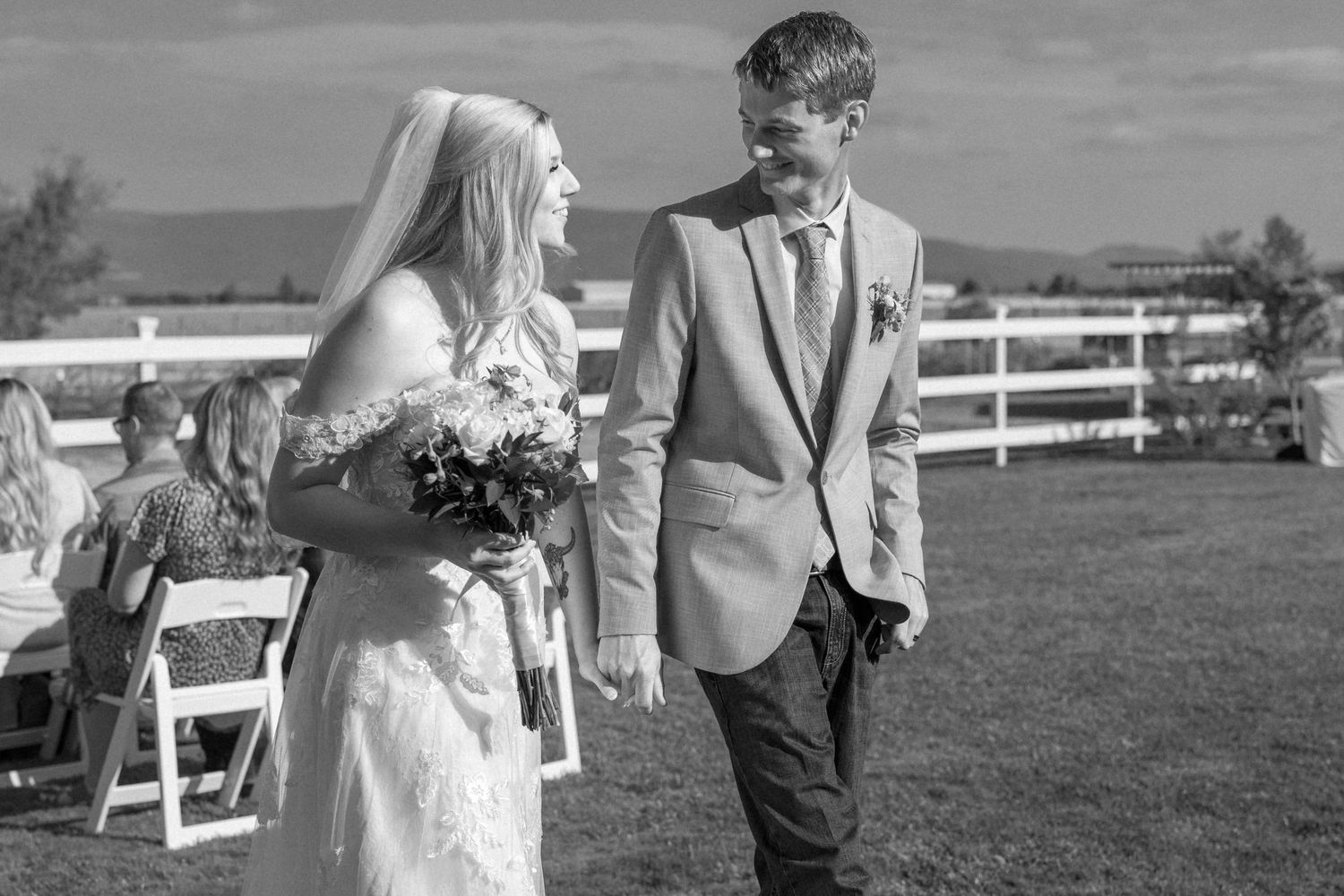 A couple shares a joyful moment together during their outdoor wedding ceremony at a rustic countryside venue.