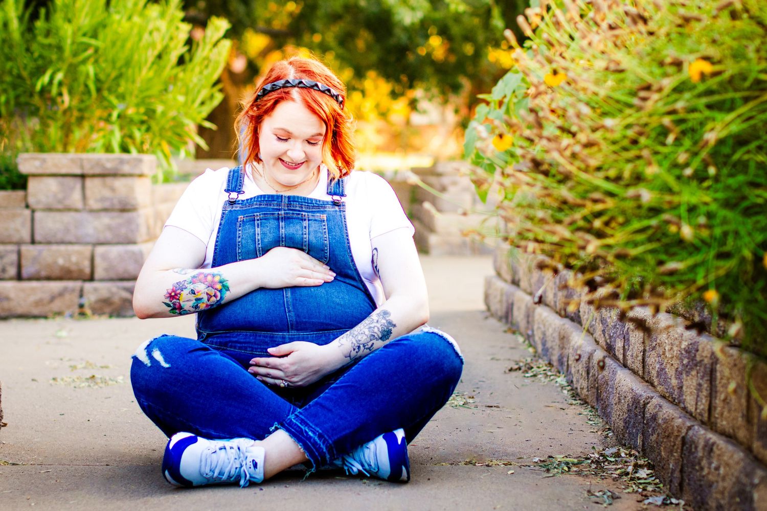 A joyful outdoor maternity session surrounded by vibrant yellow and green garden scenery.