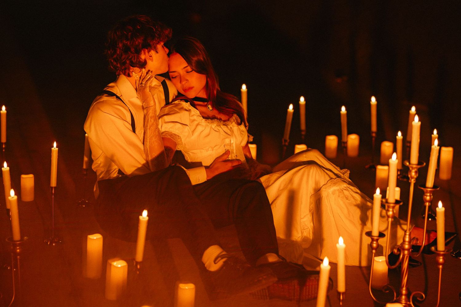 Row of glowing white candles illuminating a dark space with ethereal orange light.