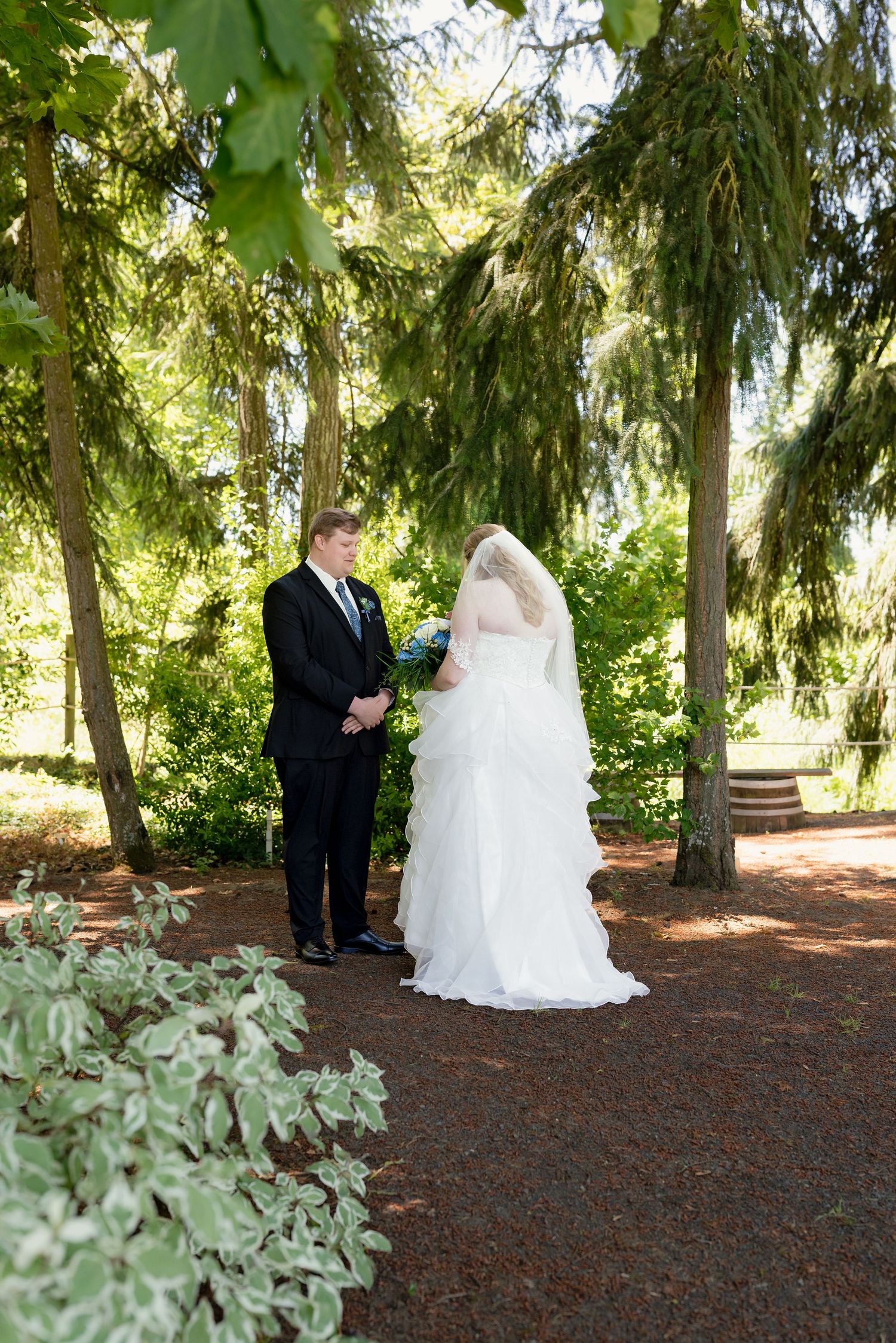 Bride and groom share a first look moment in a lush green garden.