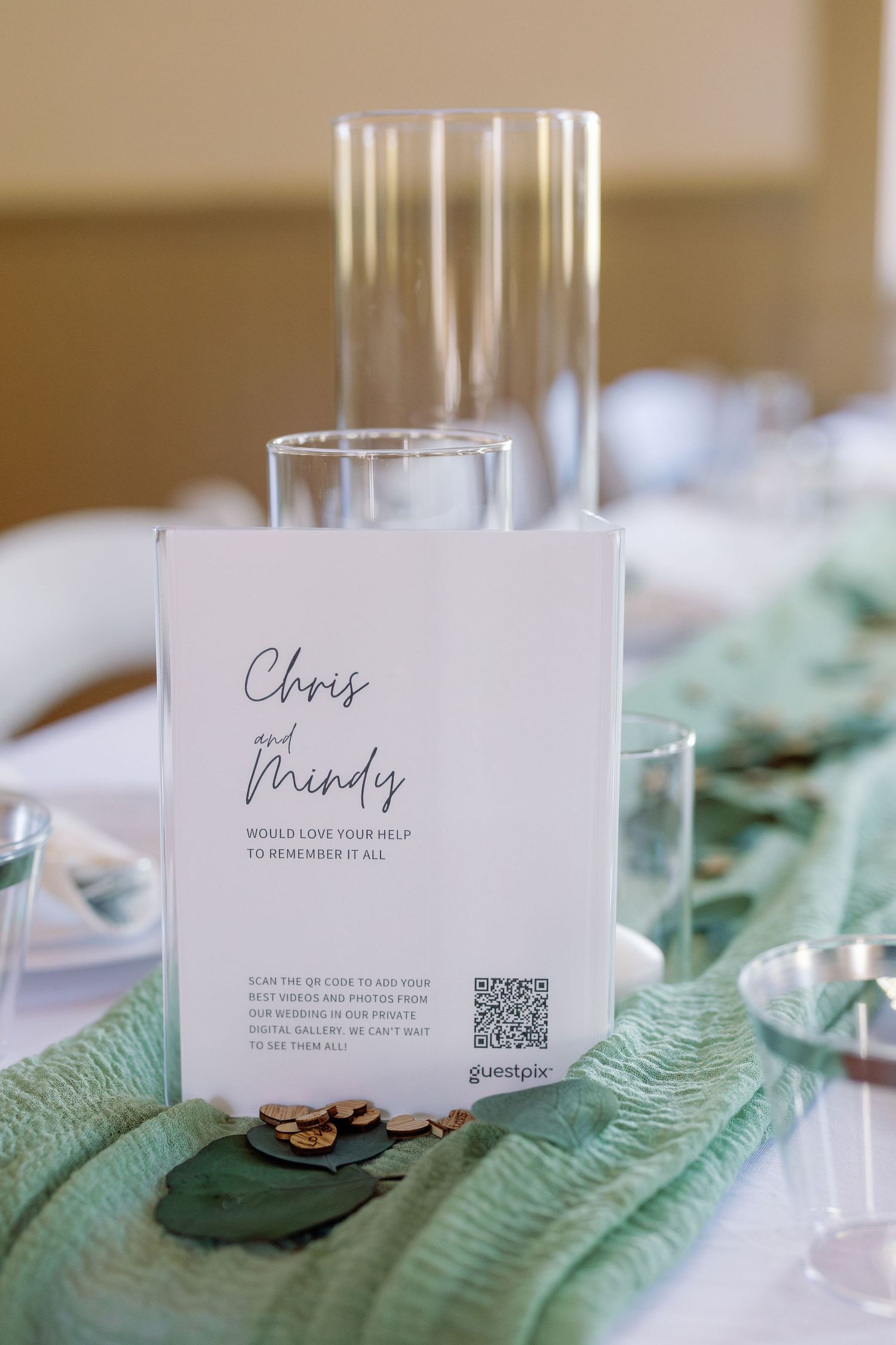 Wedding reception table setting with personalized menu card and glassware on mint green napkin.