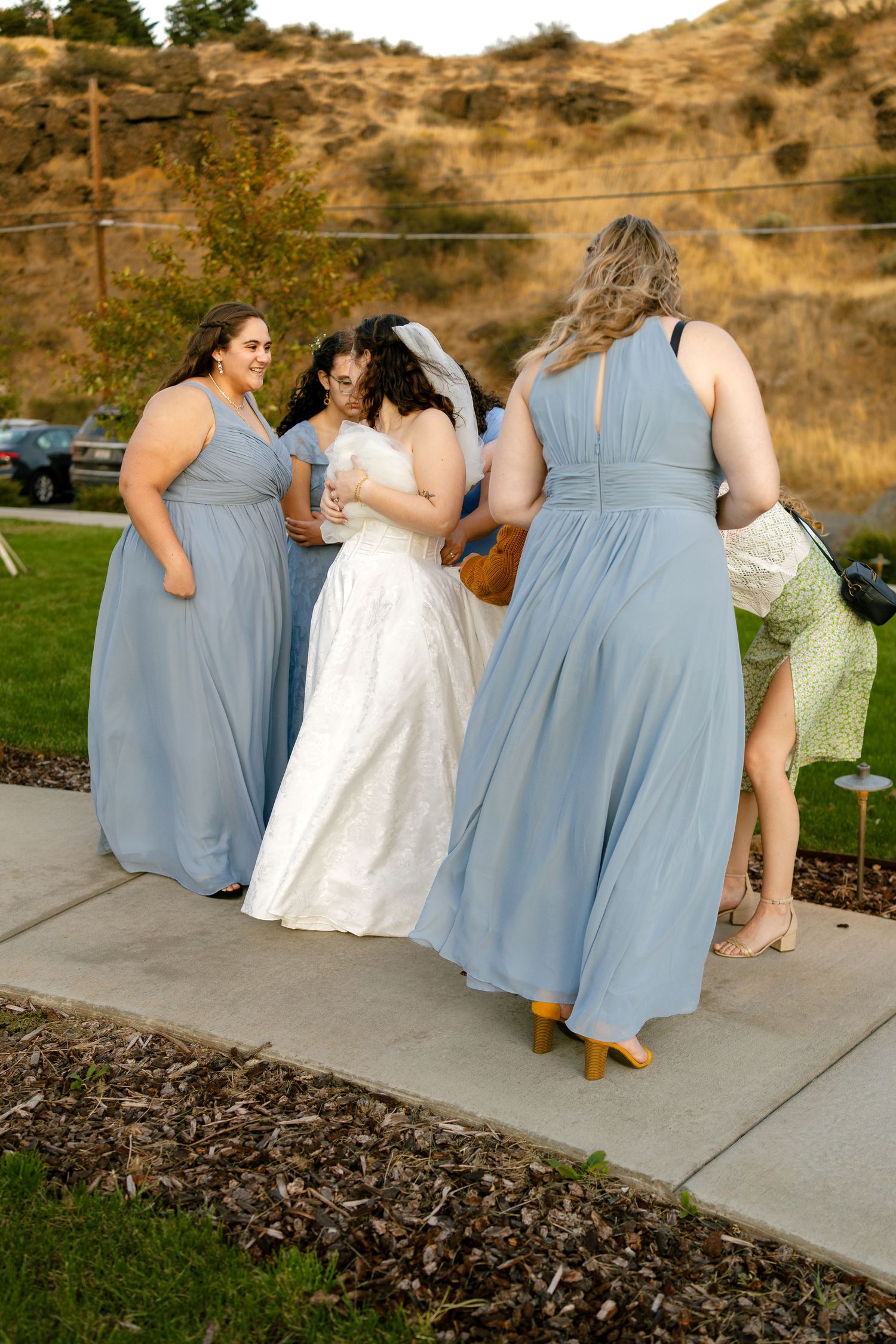 Wedding party in light blue bridesmaid dresses and white bridal gown posing outdoors.