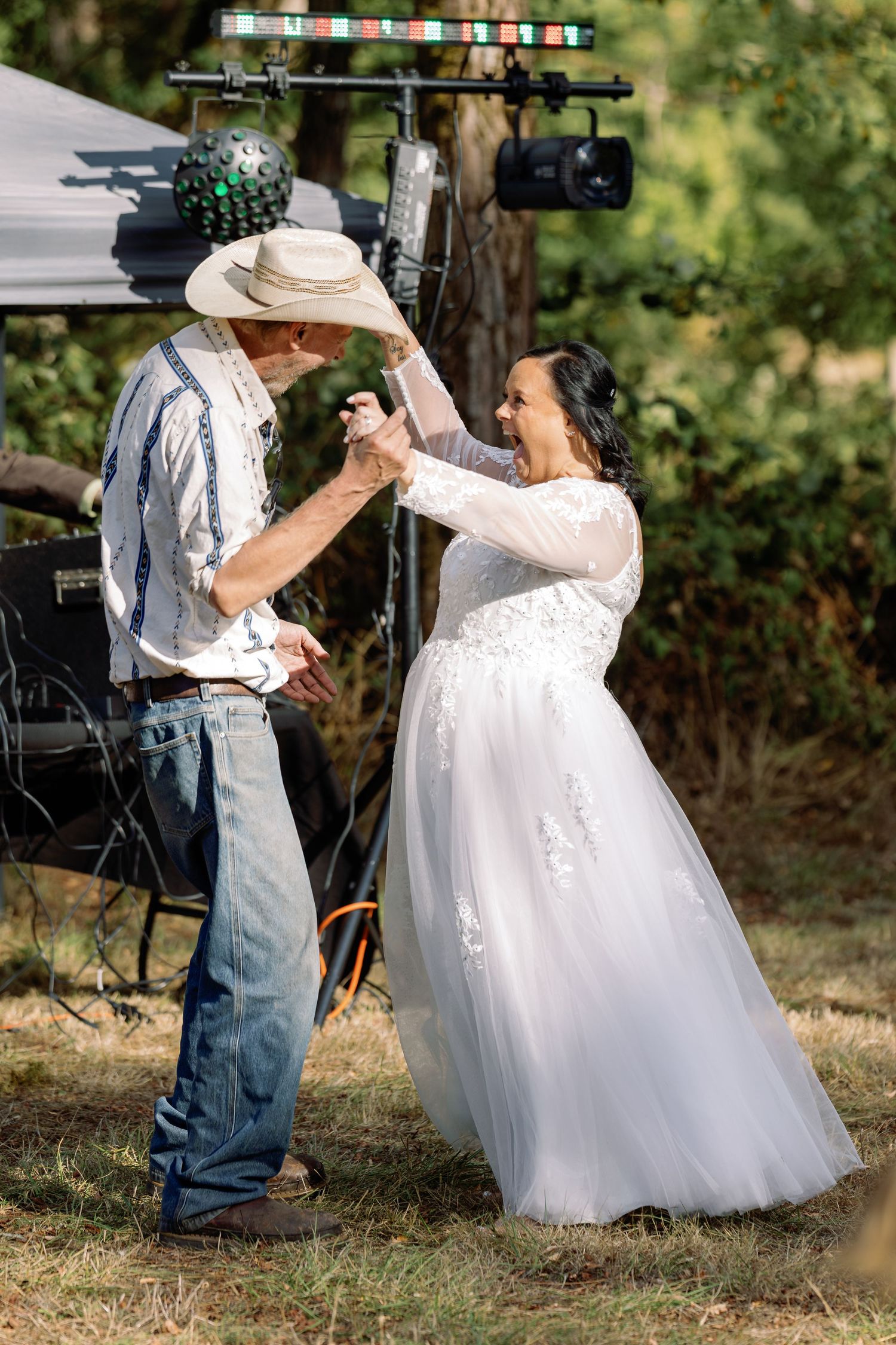 A couple dancing outdoors at a rustic wedding celebration.