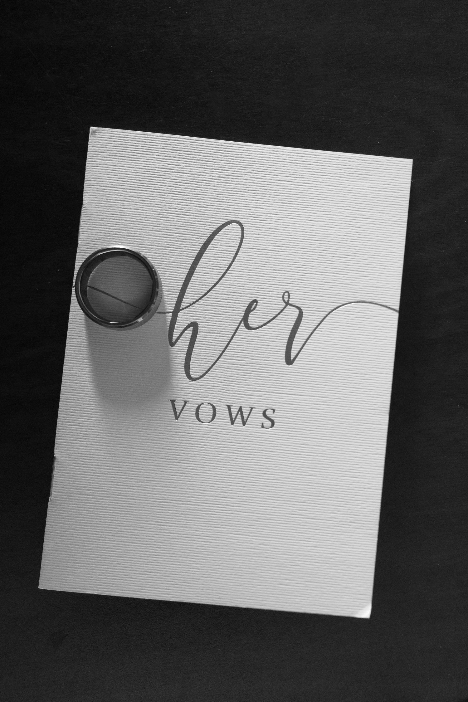 Black and white image of wedding vow cards on a textured surface.