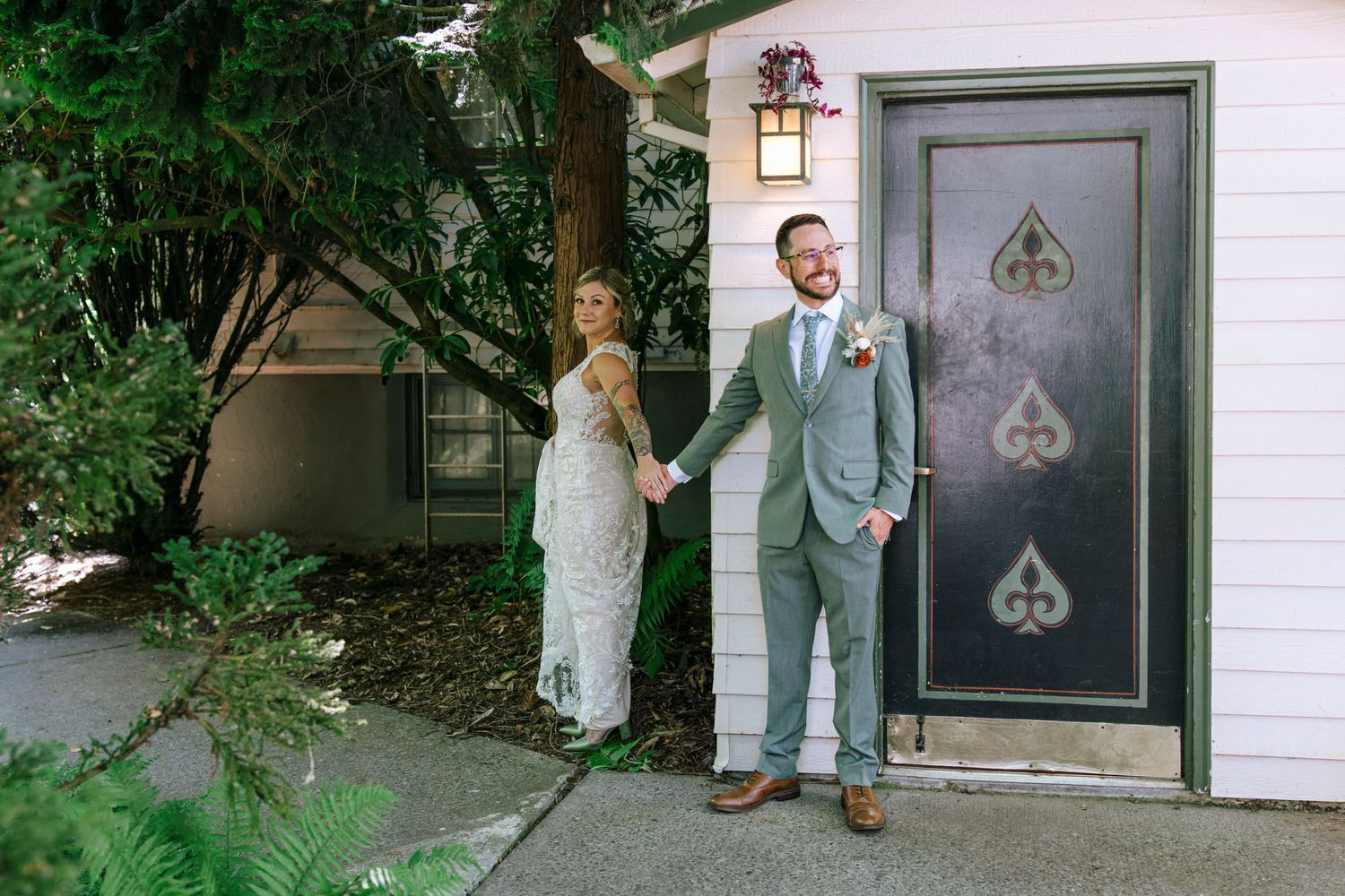 First look wedding photo of couple in front of door with spade decorations.