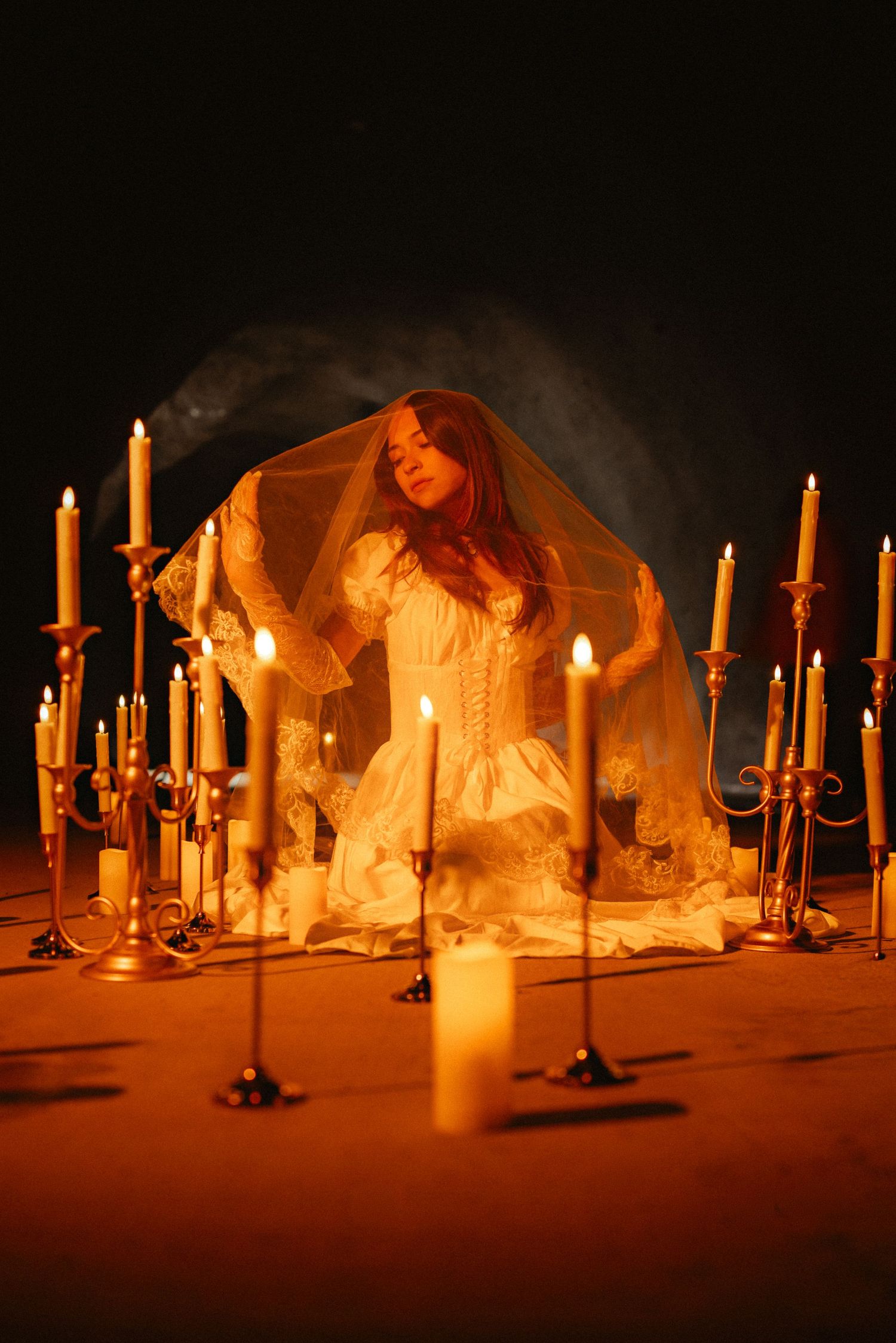 Multiple white candles illuminated in a dark room creating a warm and atmospheric glow.