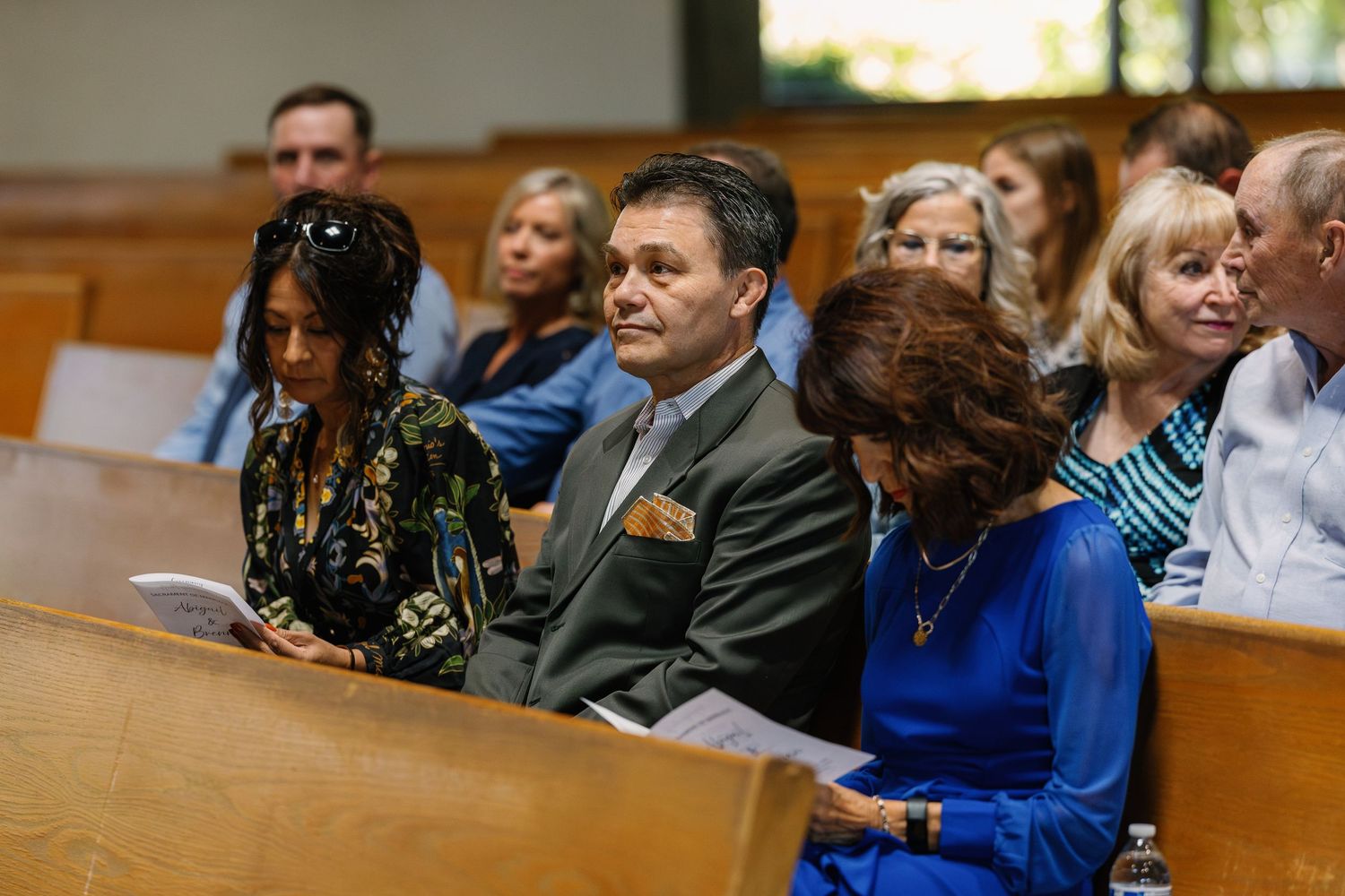 Wedding guests seated in church pews during ceremony.