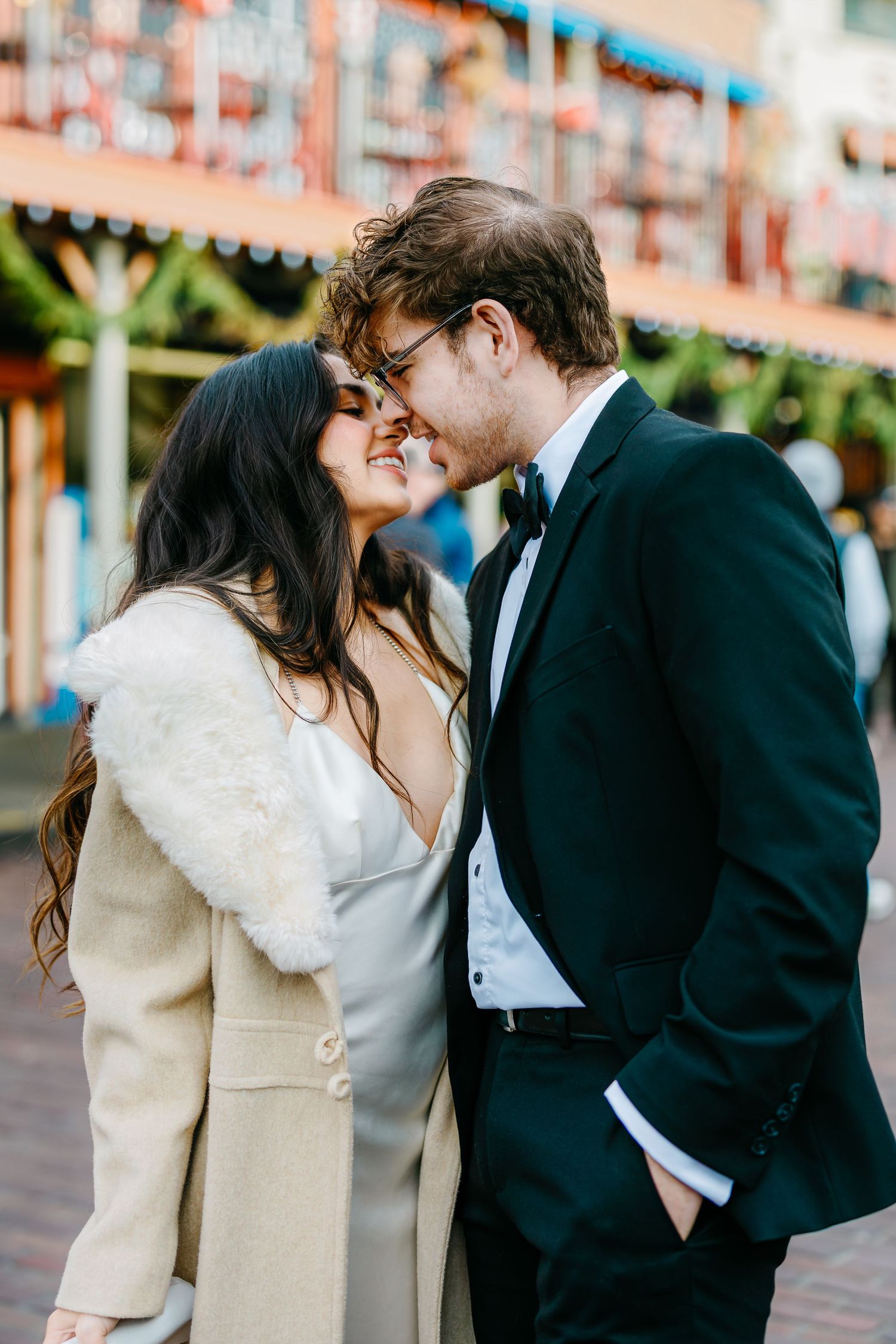 An intimate moment shared between a couple in formal attire near market stalls.