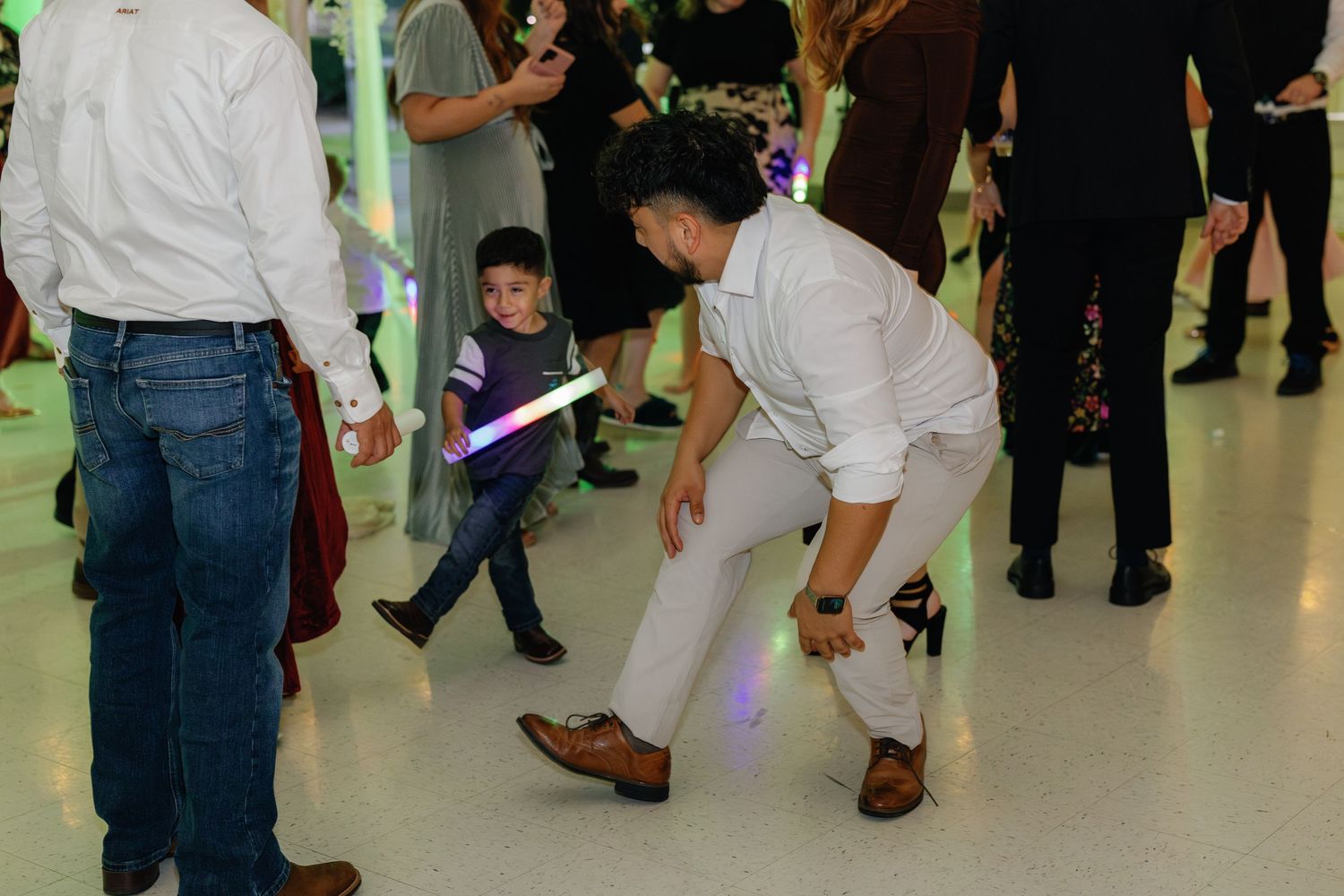 People dancing and mingling at an indoor event with colorful lighting effects.