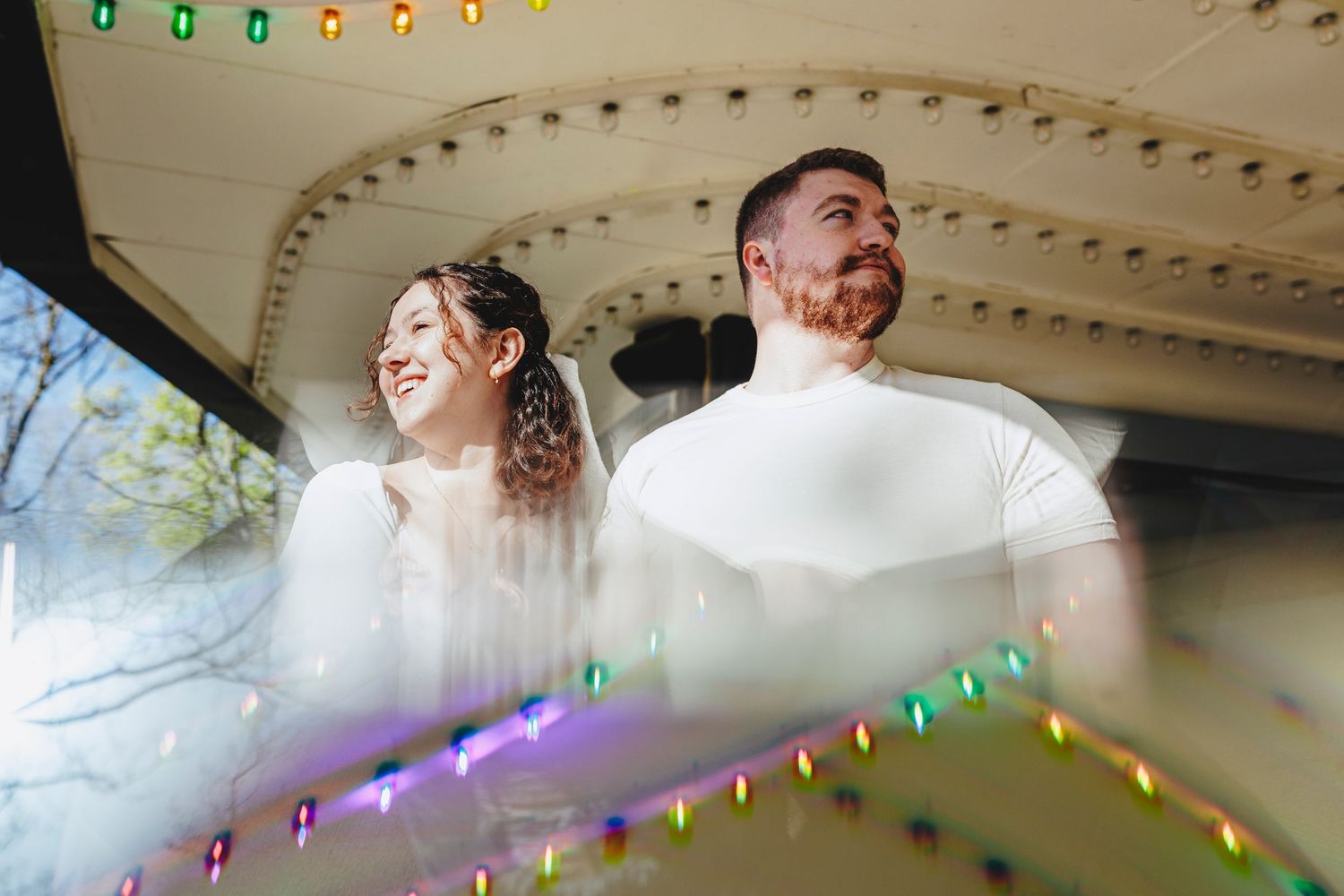 Wedding couple sharing a joyful candid moment under decorative lights and architecture.