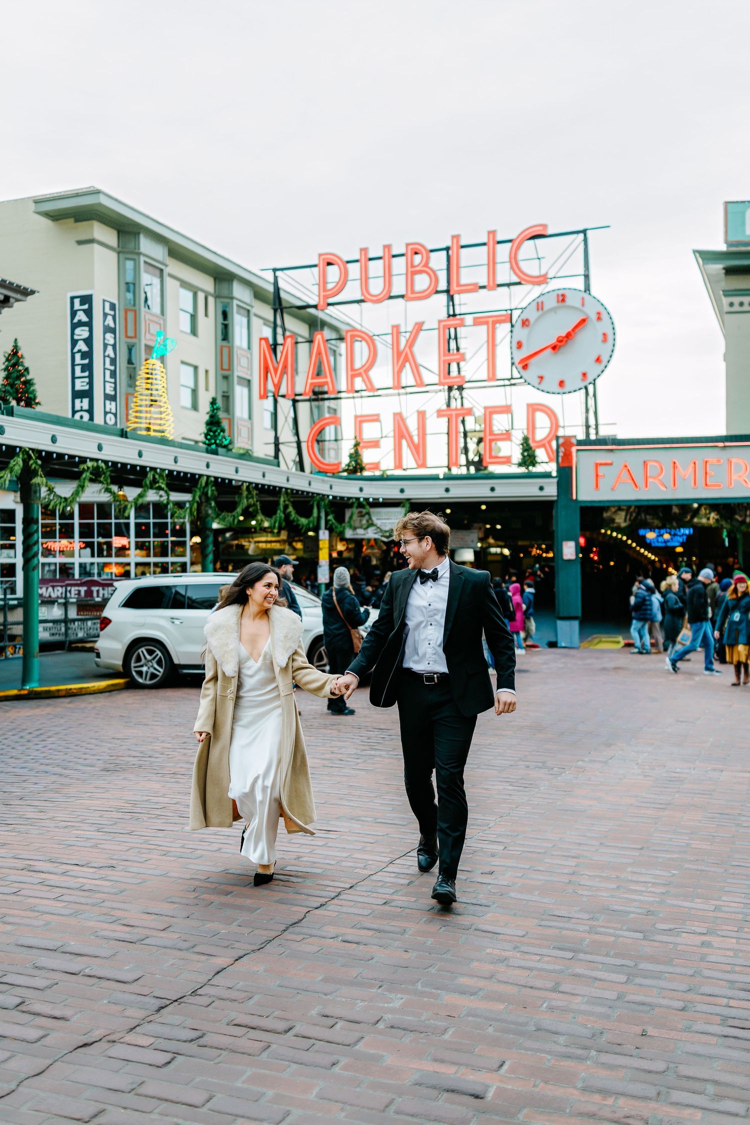 Couple walking through Pike Place Market plaza in formal attire.