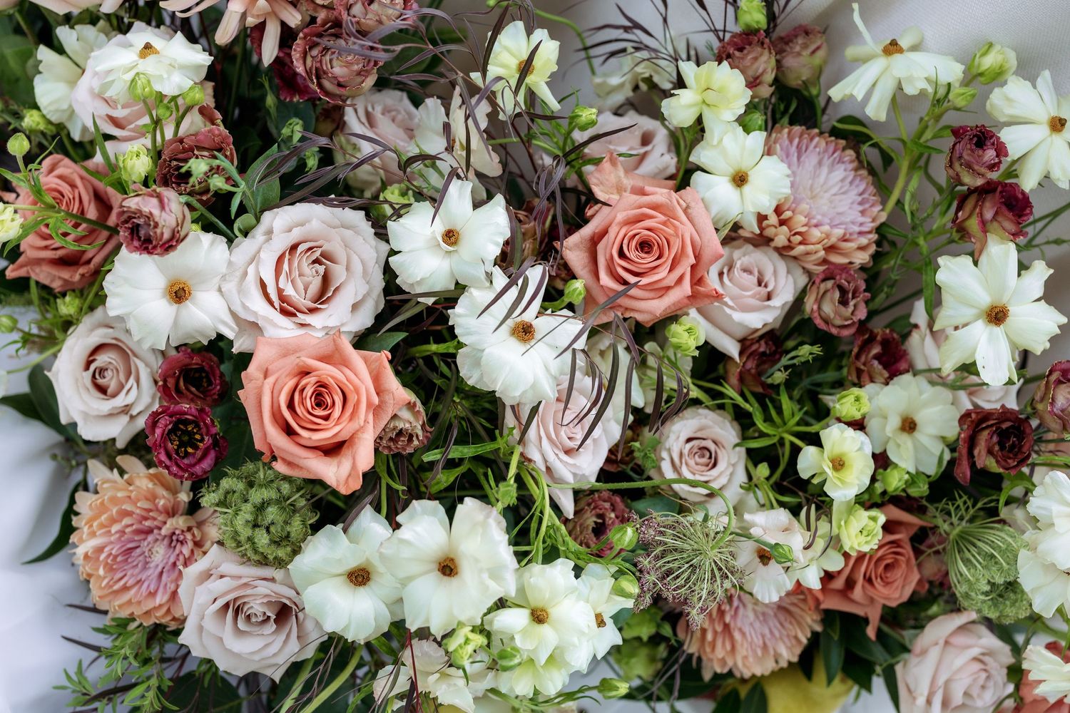 Lush floral arrangement featuring pink roses, white blooms, and greenery in romantic garden style.
