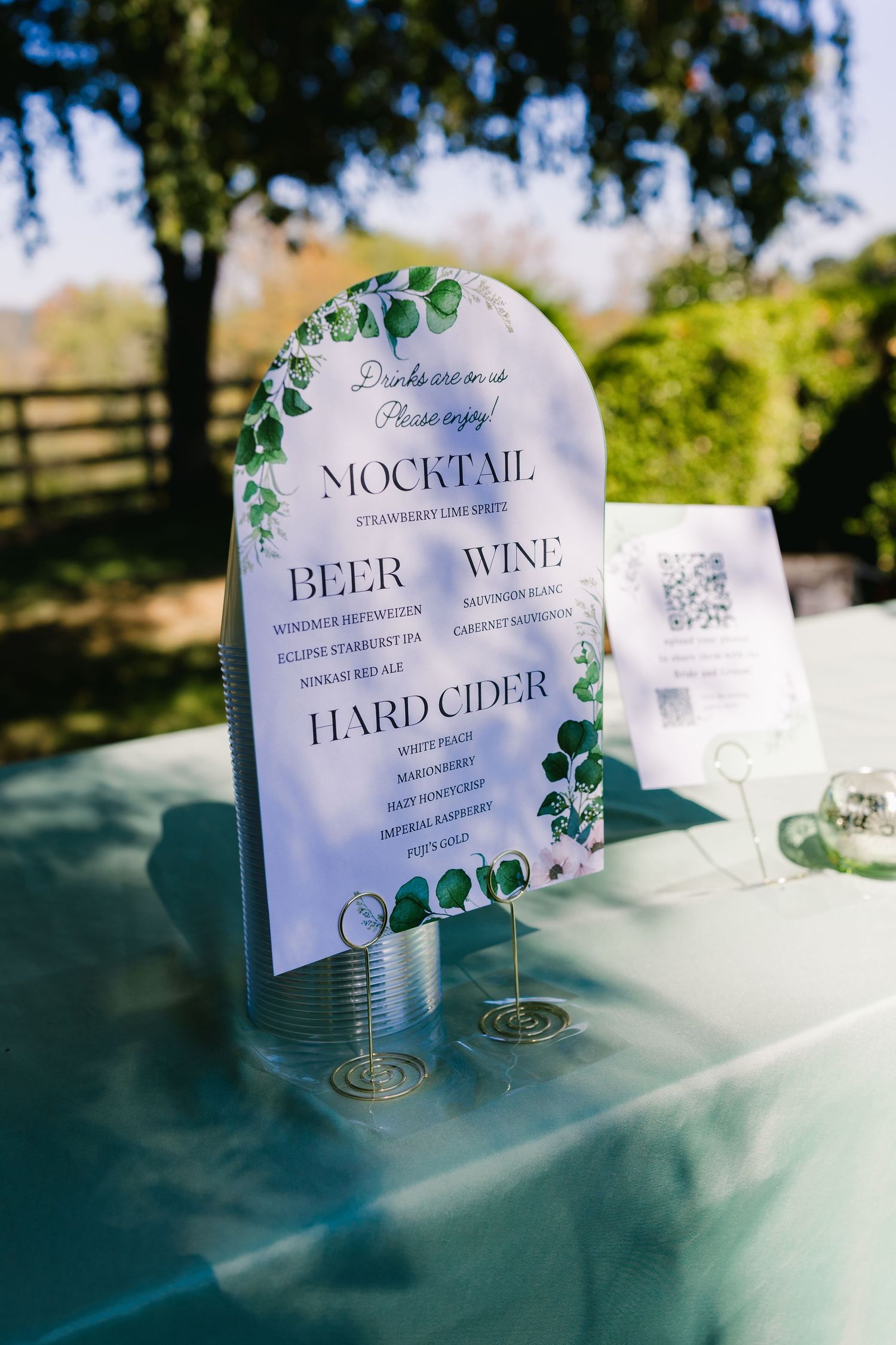Elegant drink menu signs displayed on a table for mocktails, beer, wine and hard cider.