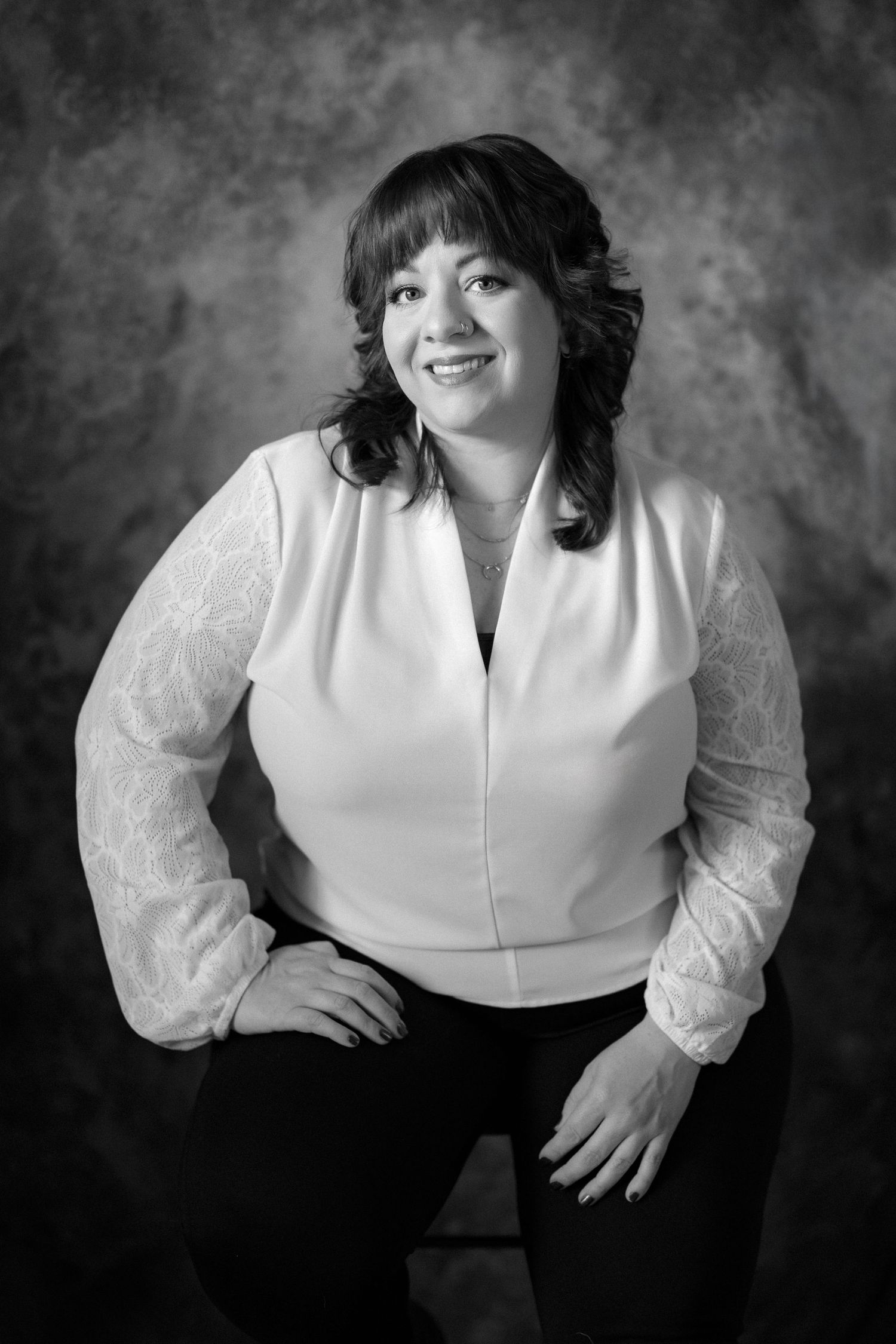 Professional black and white portrait series featuring a person in a white blouse with sheer sleeves against a dark background.