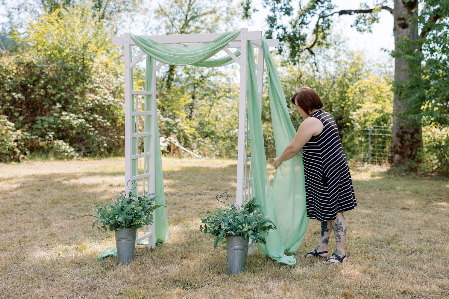Mint green fabric drapes elegantly between wooden posts in an outdoor garden setting.