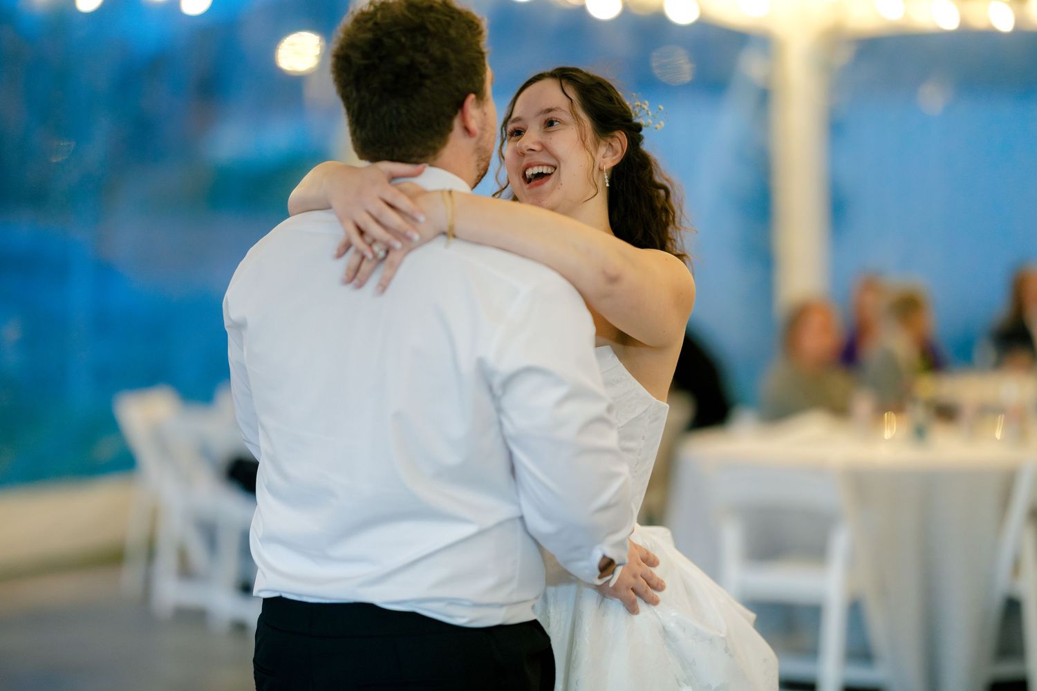 Wedding celebration on dance floor with string lights creating warm ambiance in background.