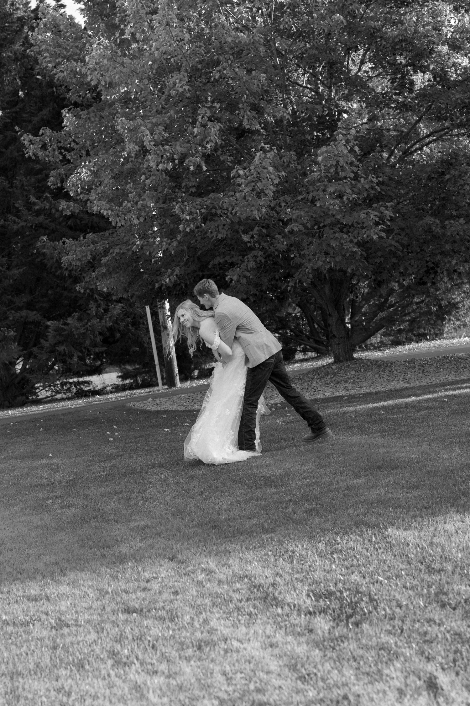 A black and white sequence showing a playful couple rolling down a grassy hill.