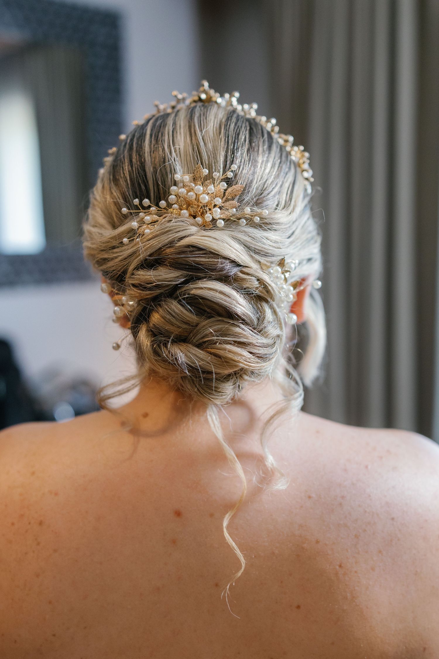 Elegant bridal hairstyle with pearl and crystal hair accessories shown in close-up detail.
