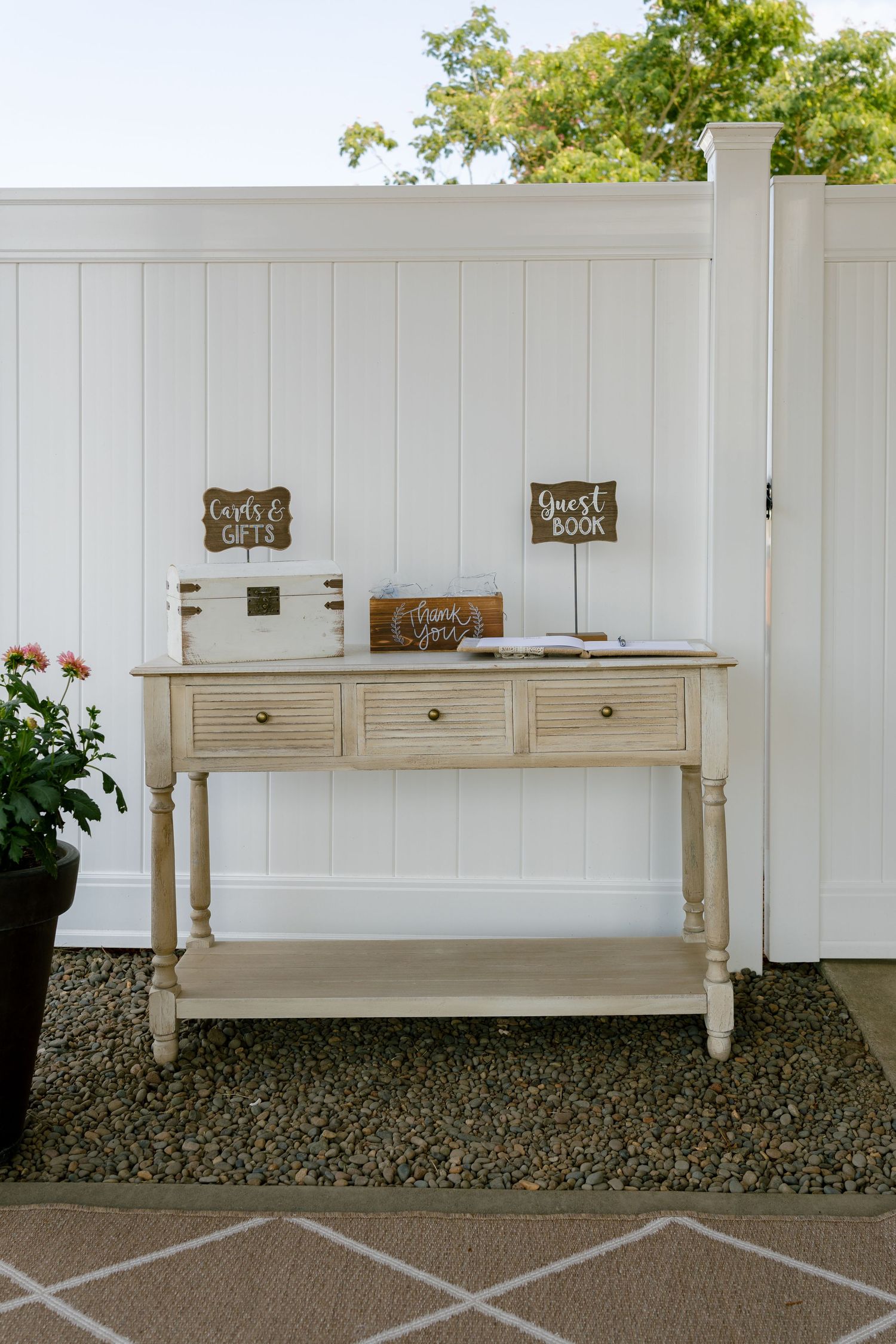 White vintage console tables lined up against a white fence for wedding decor.