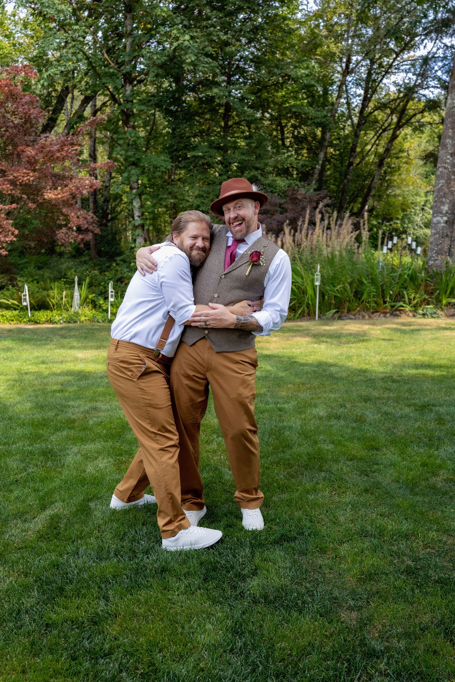 Playful wedding photos on a grassy lawn showing coordinated brown outfits.