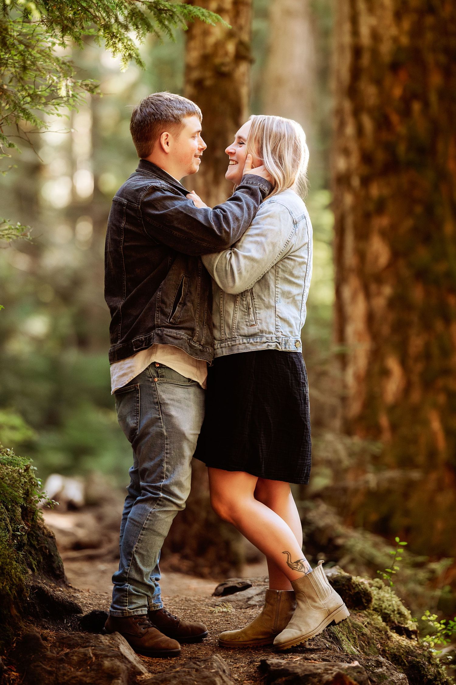 Two young children in casual attire share a tender moment while playing in a sunlit forest setting.