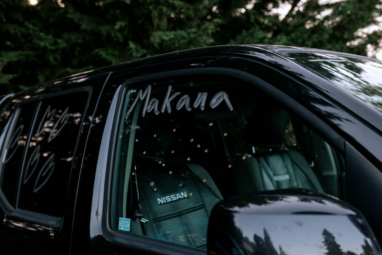 Black Nissan SUV window decorated with the names Victoria and Makana in white script for a wedding getaway car.
