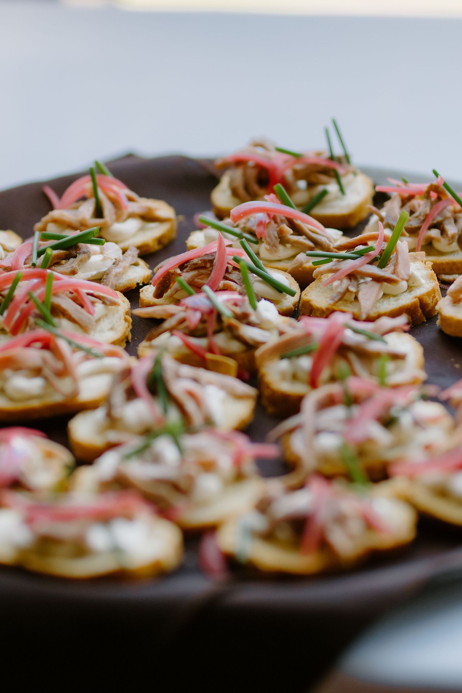 Elegant wedding appetizers of potato rounds topped with cream, pickled onions, and fresh chives.