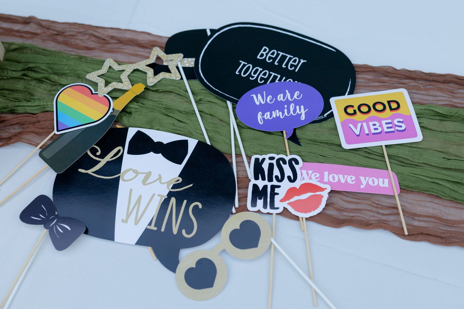 Colorful wedding photo booth props on sticks including fun signs with love messages and party accessories.