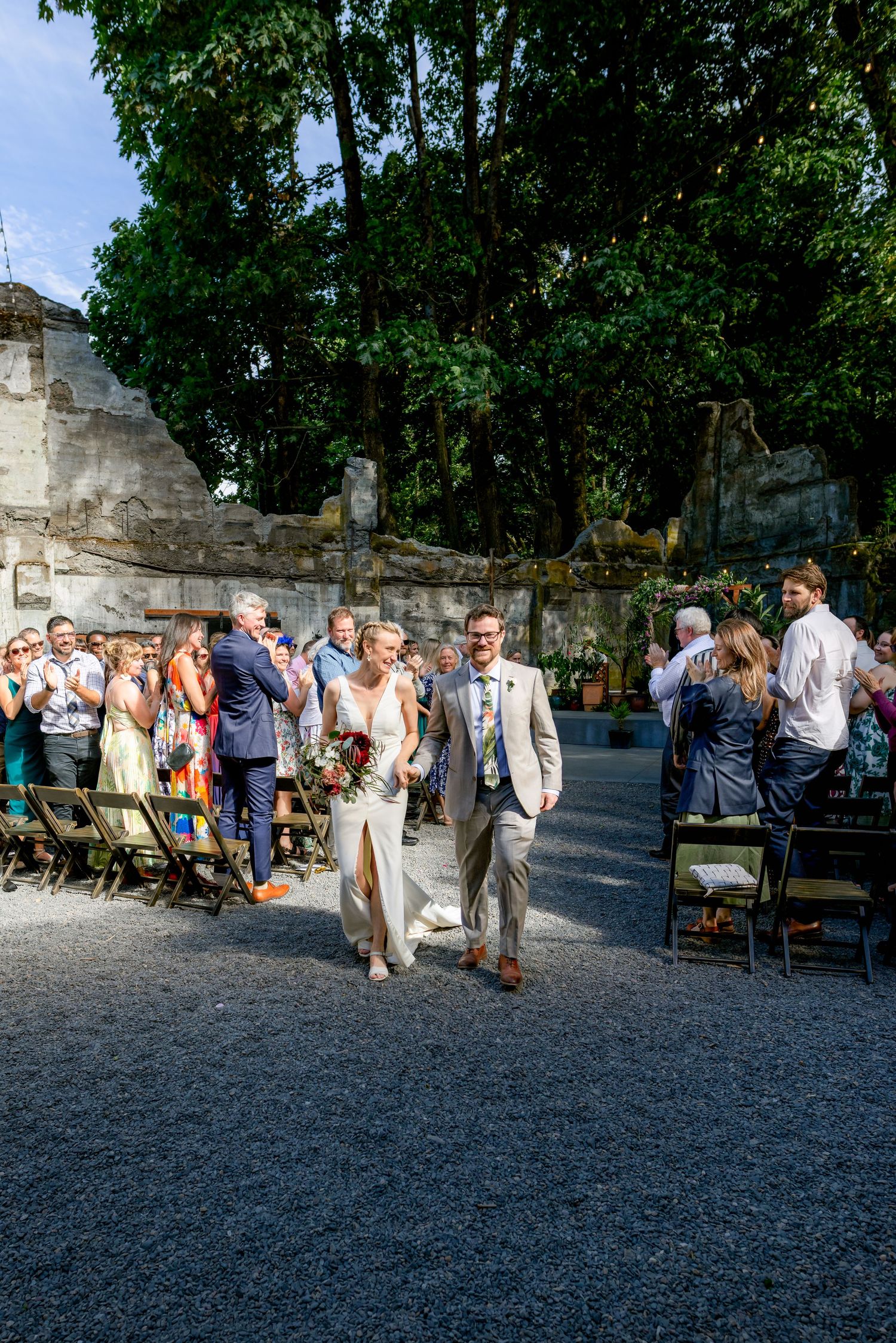 Newlyweds walking down aisle at outdoor wedding.