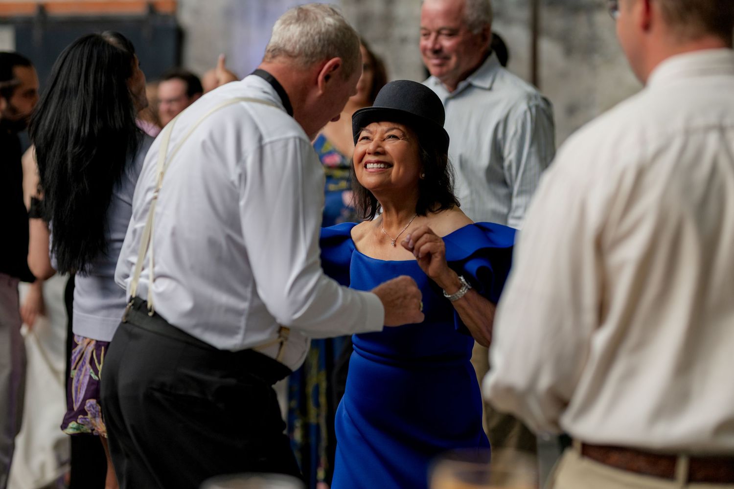 Guests in formal attire mingle and dance together at an elegant wedding reception.