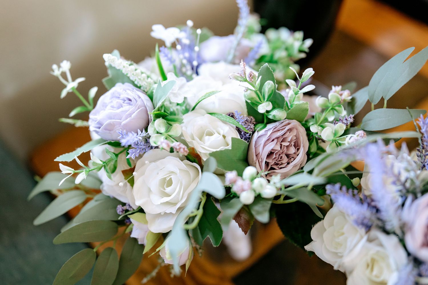 Elegant wedding bouquet featuring lavender roses, white blooms, eucalyptus, and delicate berries in a soft romantic arrangement.