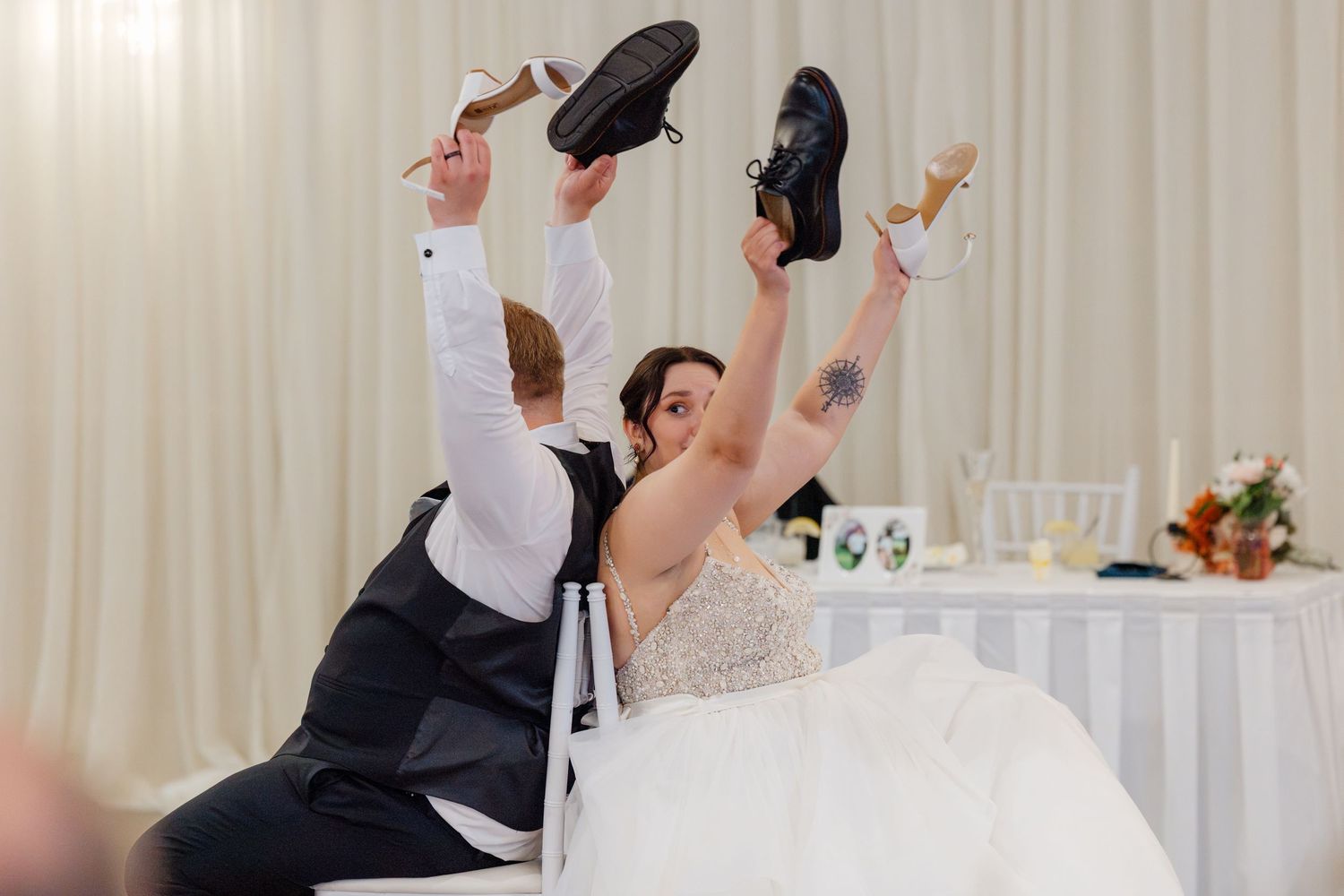 Bride and groom hold up shoes during fun wedding reception shoe game activity.