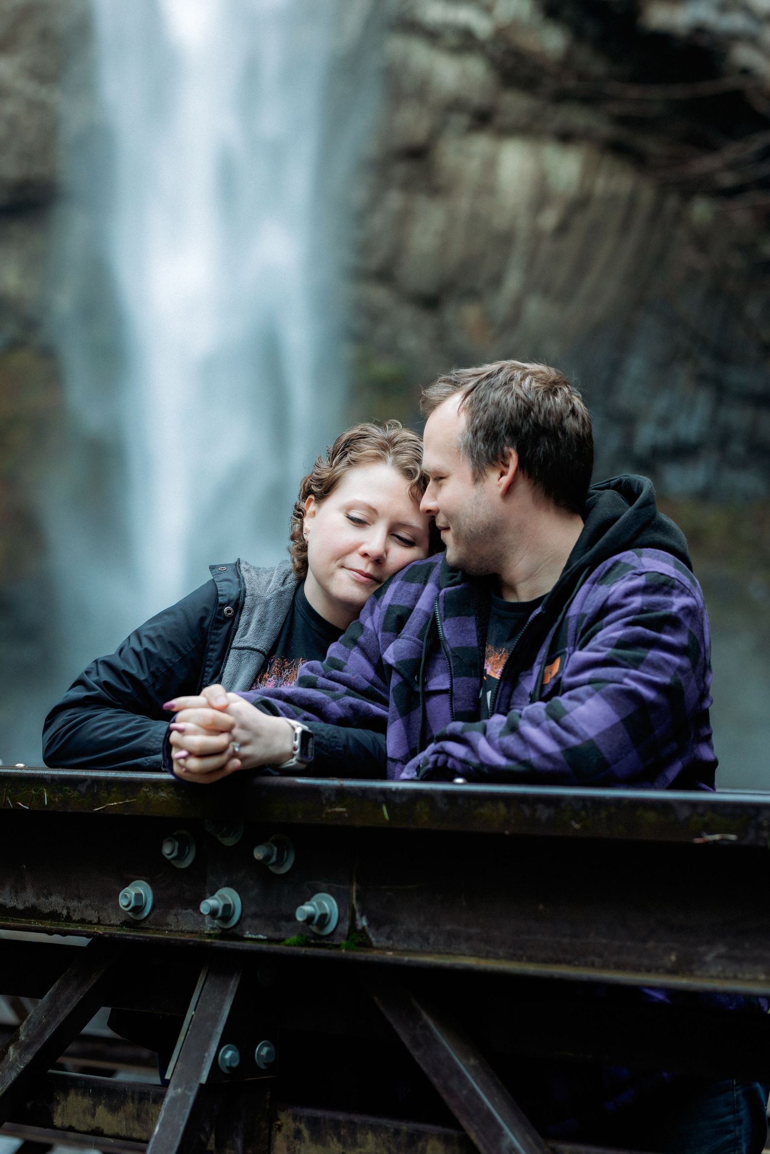 A wooden observation deck overlooks a majestic waterfall flowing from tall cliffs.