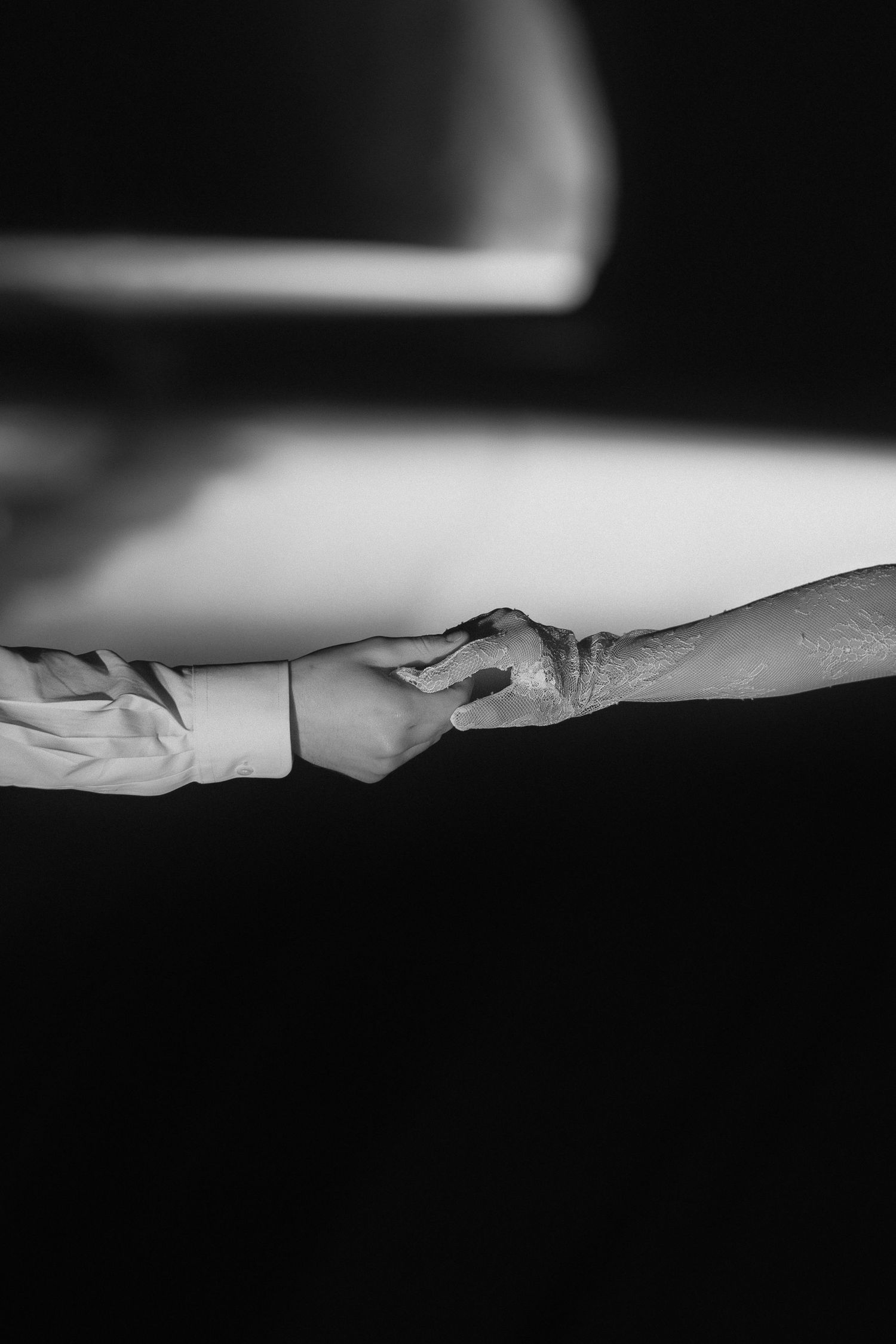 Abstract black and white photograph showing soft curved lines and shadows against a light background.