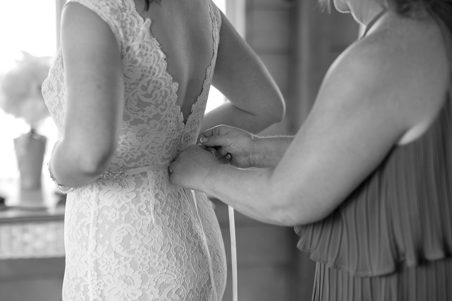 Close-up details of lace wedding dress being adjusted.