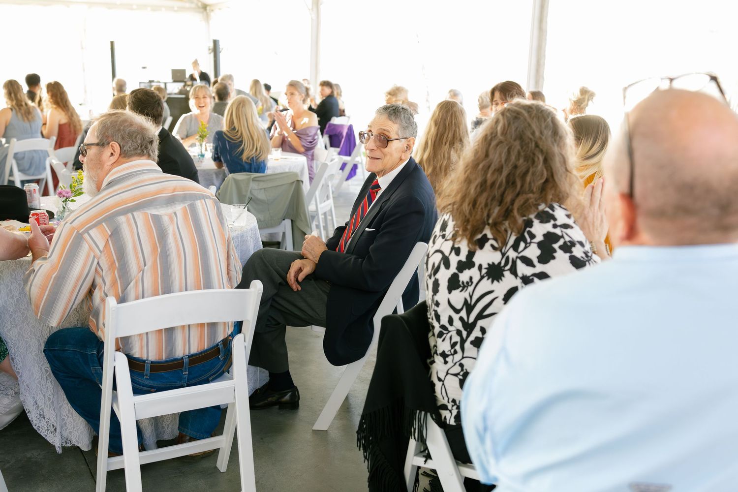 Wedding reception venue with guests seated at tables decorated in blue and white.