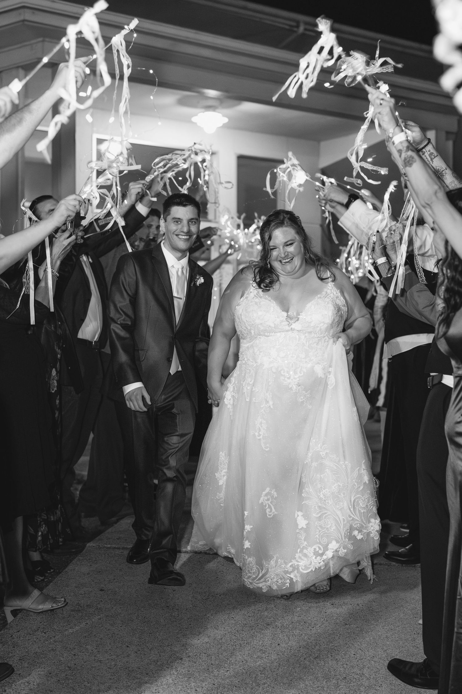 Wedding party celebrates under streaming white ribbons during an evening reception.