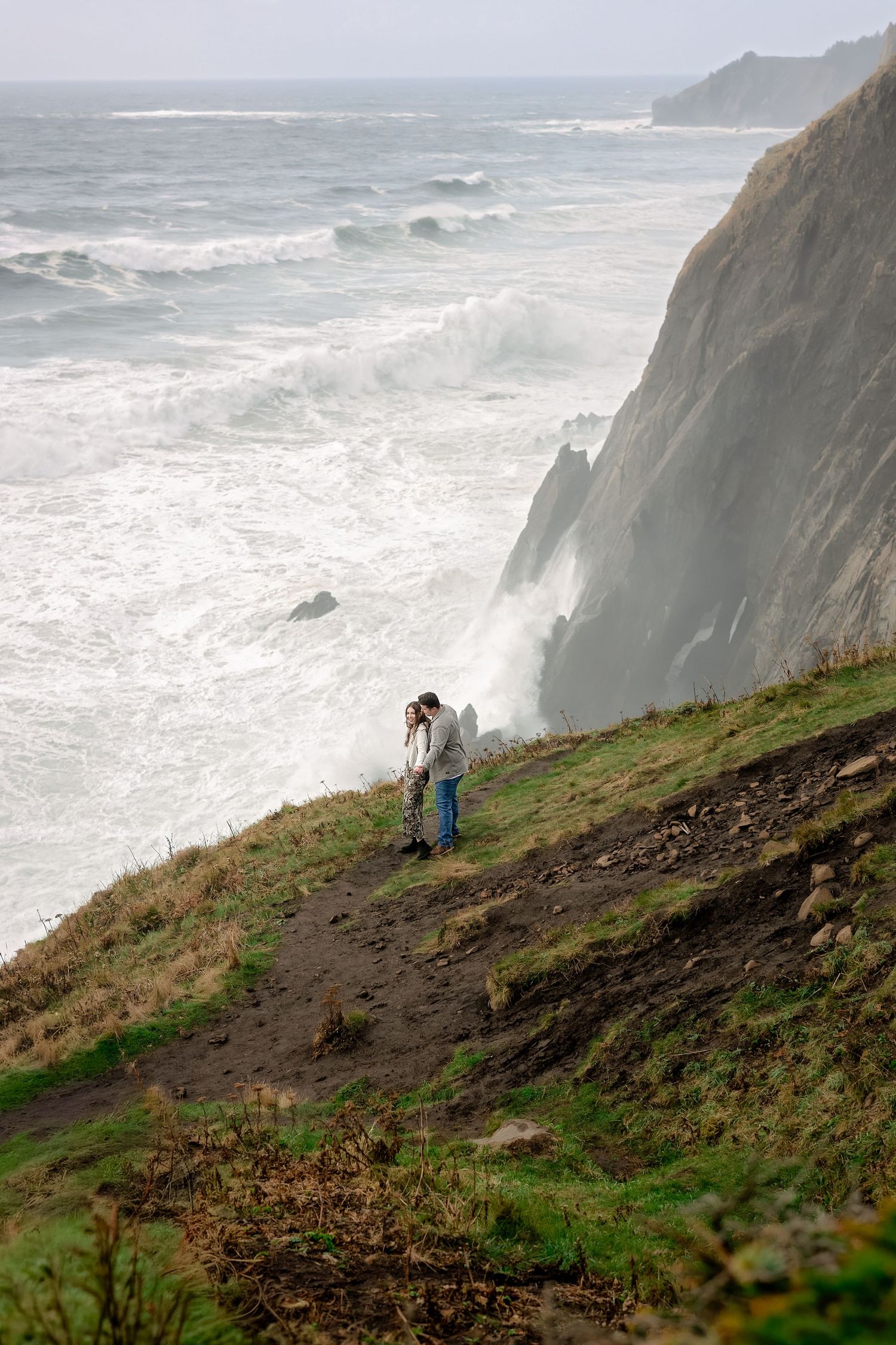 Dramatic coastal cliffs meet the Pacific Ocean with tiny figures visible on the hillside path.