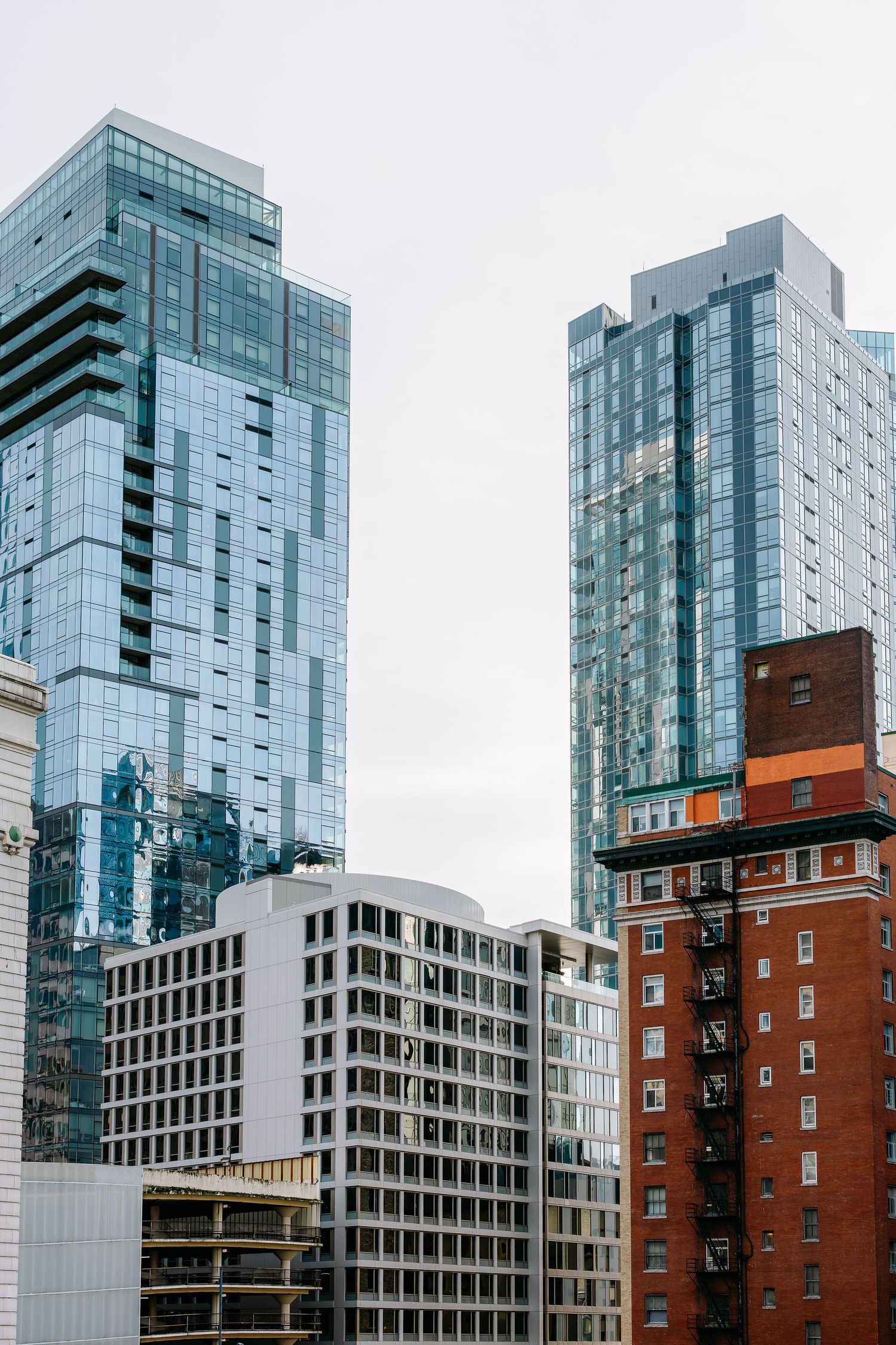 Modern glass high-rise buildings contrasting with historic brick architecture in urban setting.