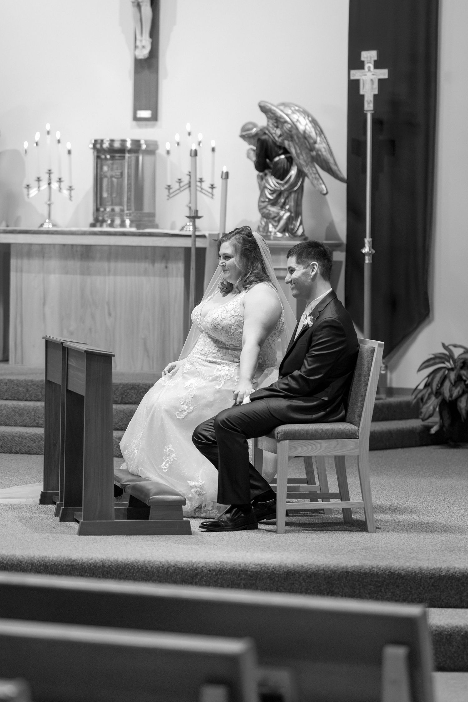 A black and white photo of a couple seated during their traditional church wedding ceremony.