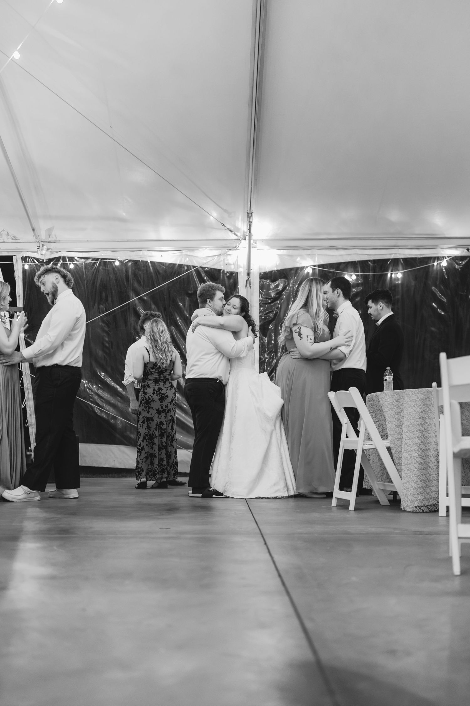 Wedding reception dance under white tent with string lights and couples dancing.