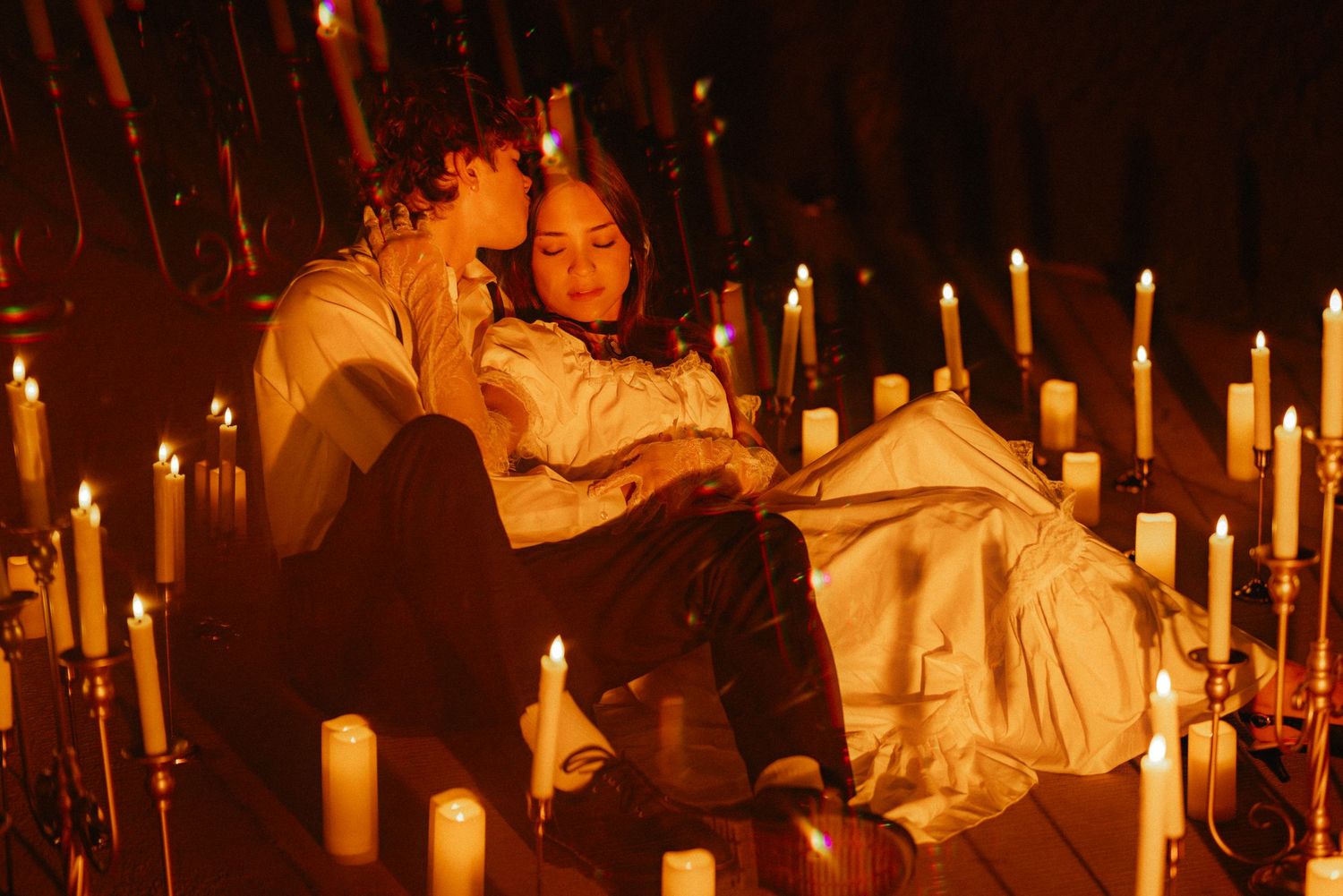 A candlelit medieval-style banquet scene with people in period costumes dining at long wooden tables.
