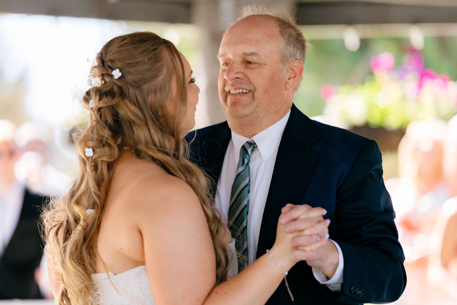 Bride and father share emotional first dance, smiling warmly at each other during wedding reception.