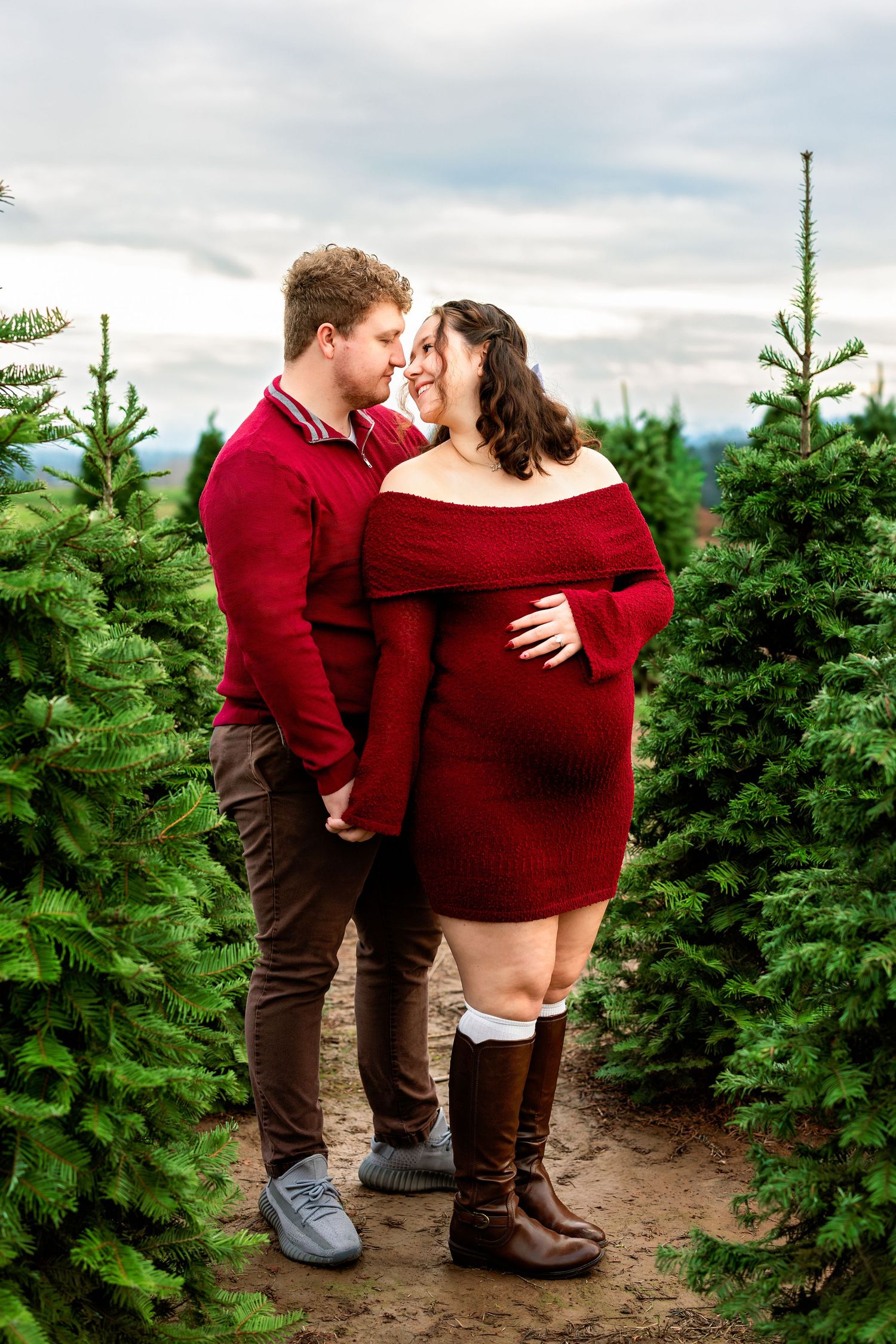 A romantic couple moment among evergreen trees at a Christmas tree farm.