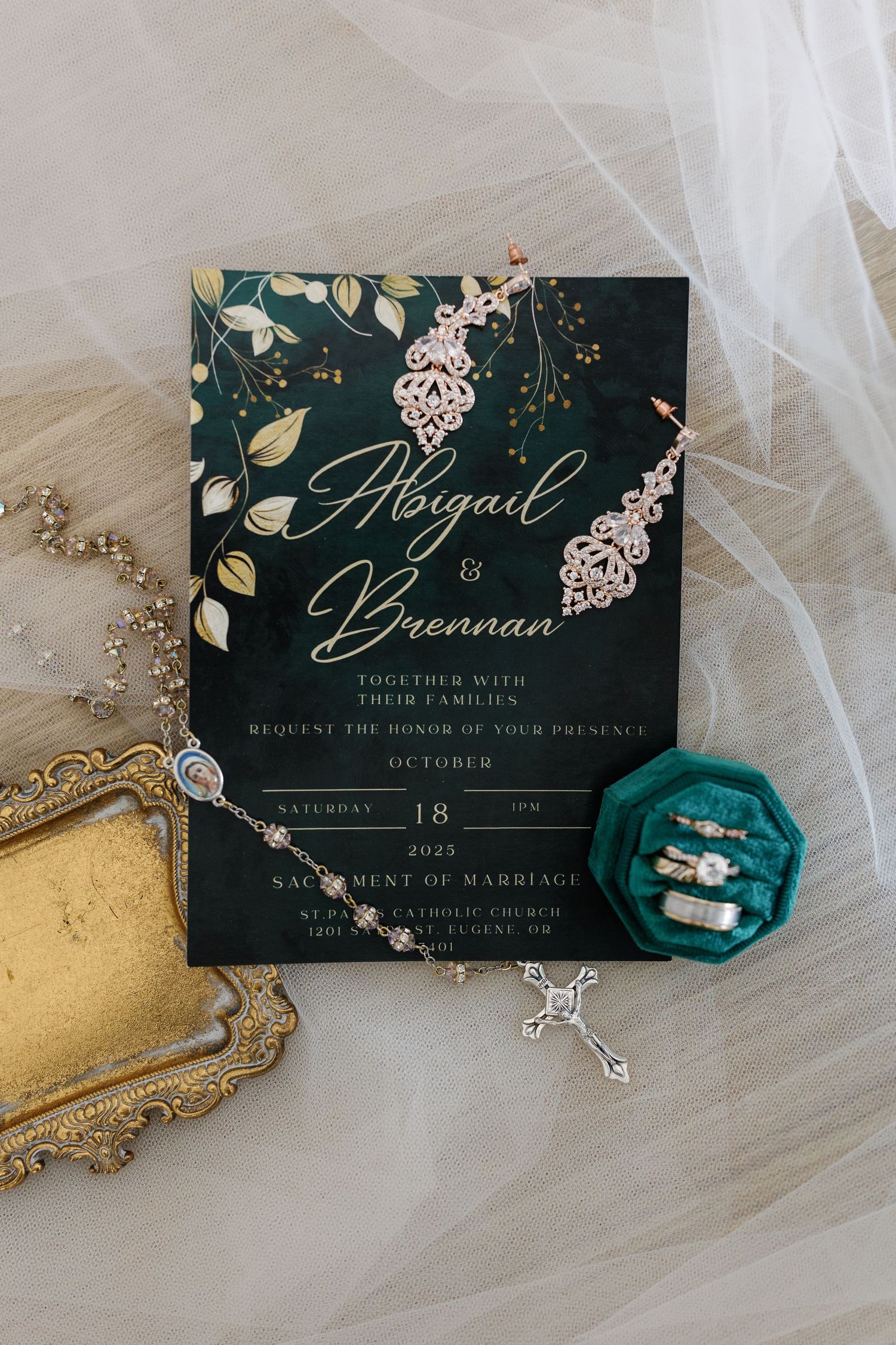 Elegant wedding invitation with floral design on dark background alongside jewelry and decorative elements.