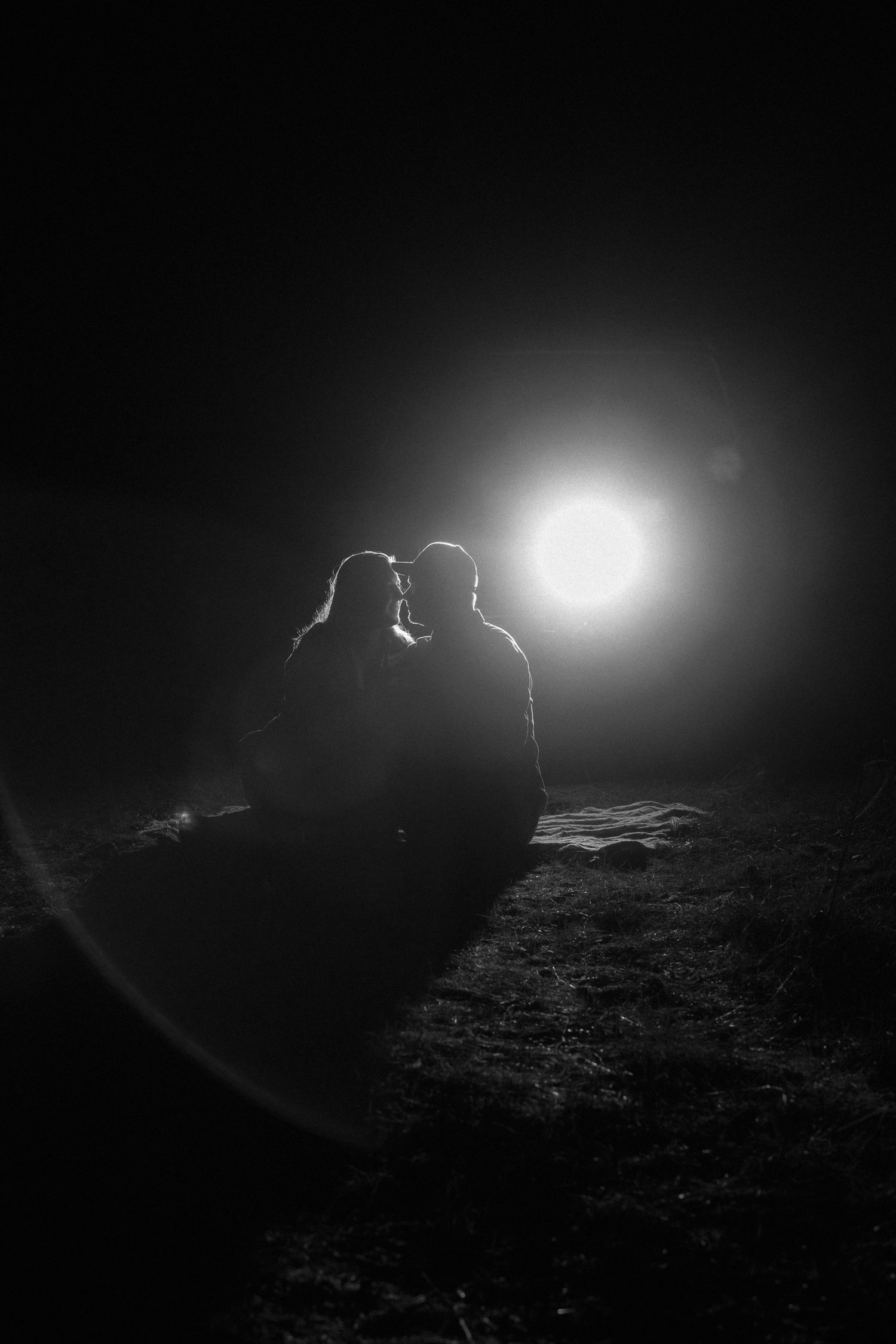 Silhouettes stand against a bright light in a dark landscape creating a dramatic atmospheric sequence.