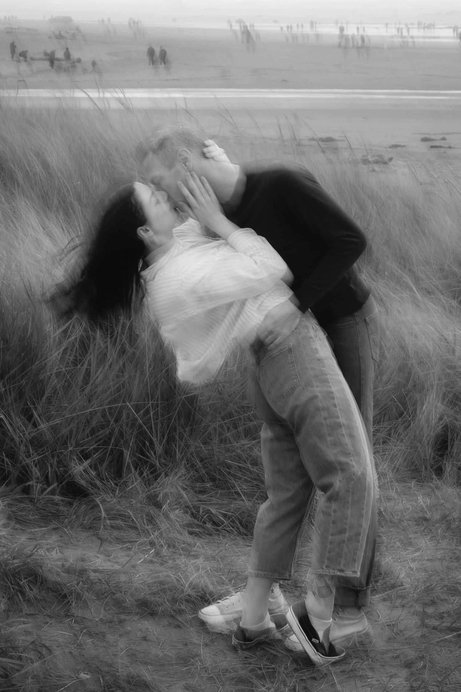 A romantic black and white photograph shows a couple embracing in tall grass with a dreamy, artistic composition.