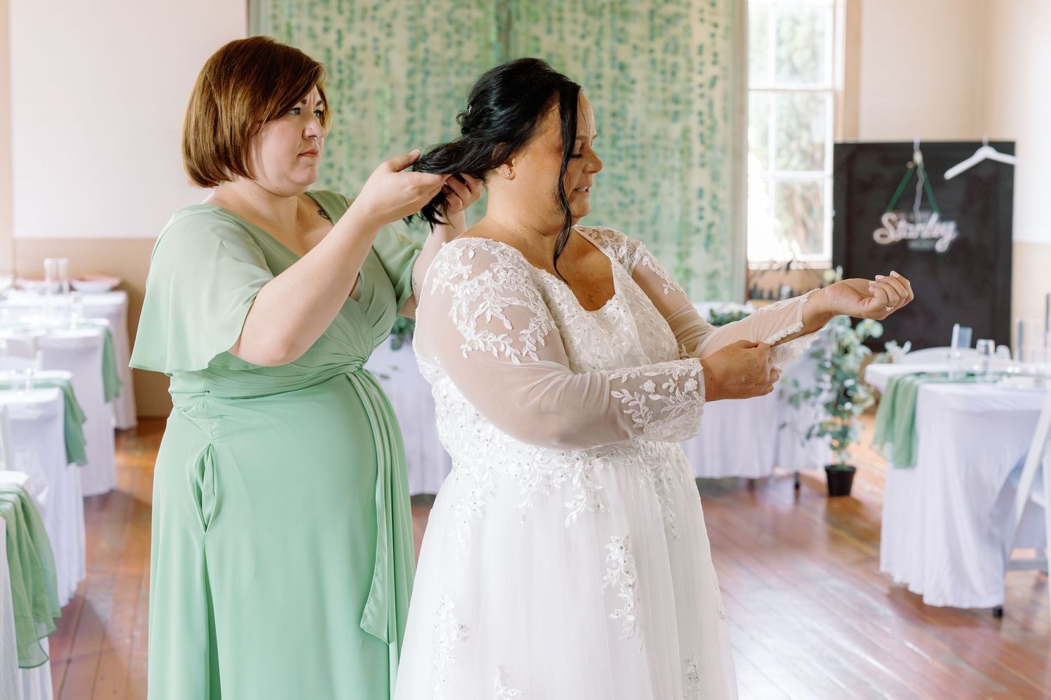 Wedding guests dancing together in a reception hall decorated with mint green and white decor.