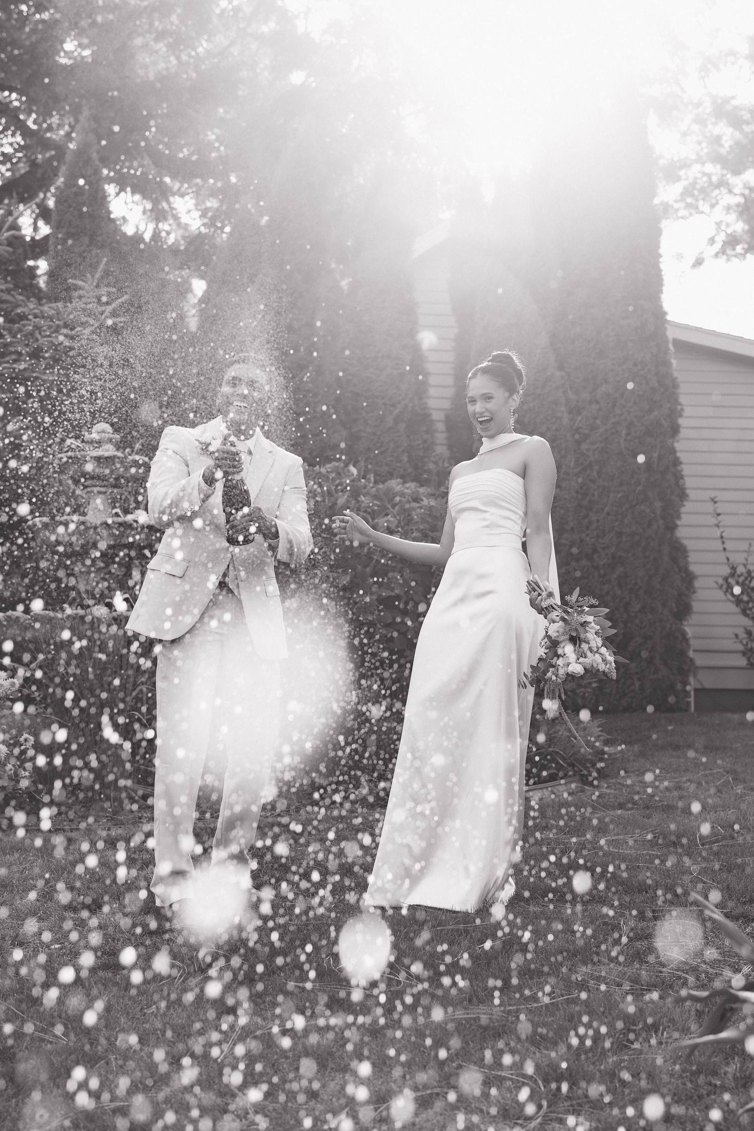 A dreamy black and white photo series shows a person in a flowing white dress twirling in a sunlit garden.