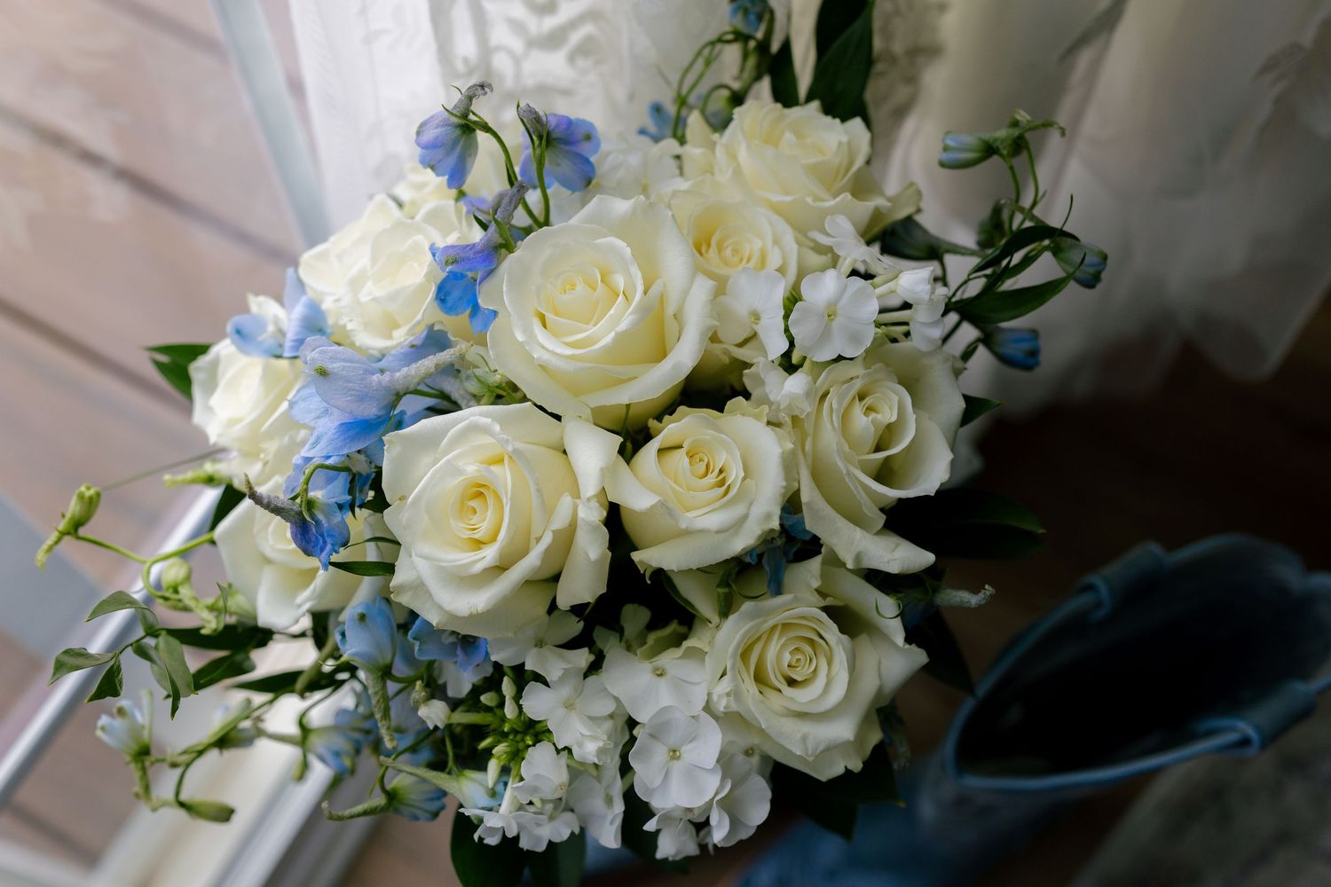 An elegant bouquet of white roses and blue flowers arranged for a wedding.